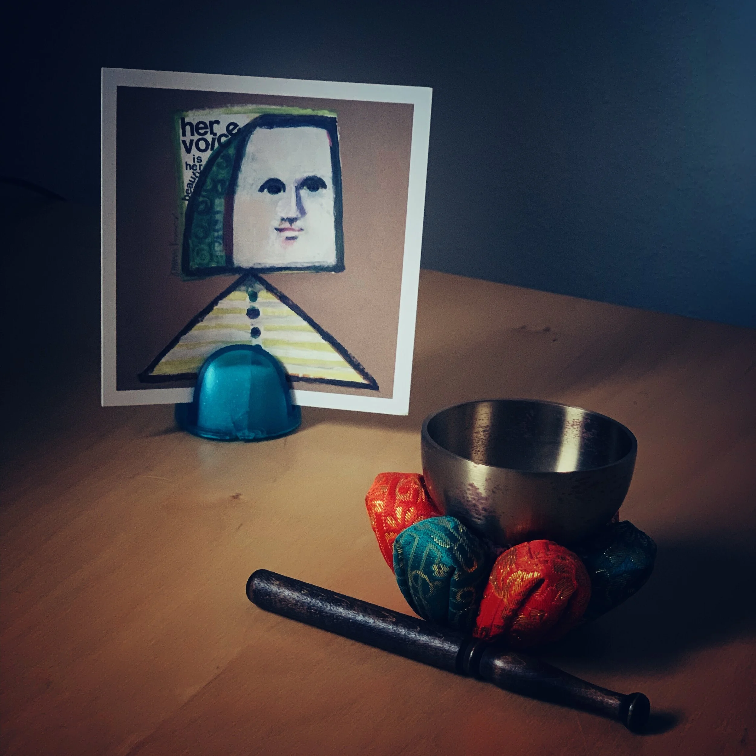 Desk with card that says Her Voice is her beauty. Small Tibetan bowl.