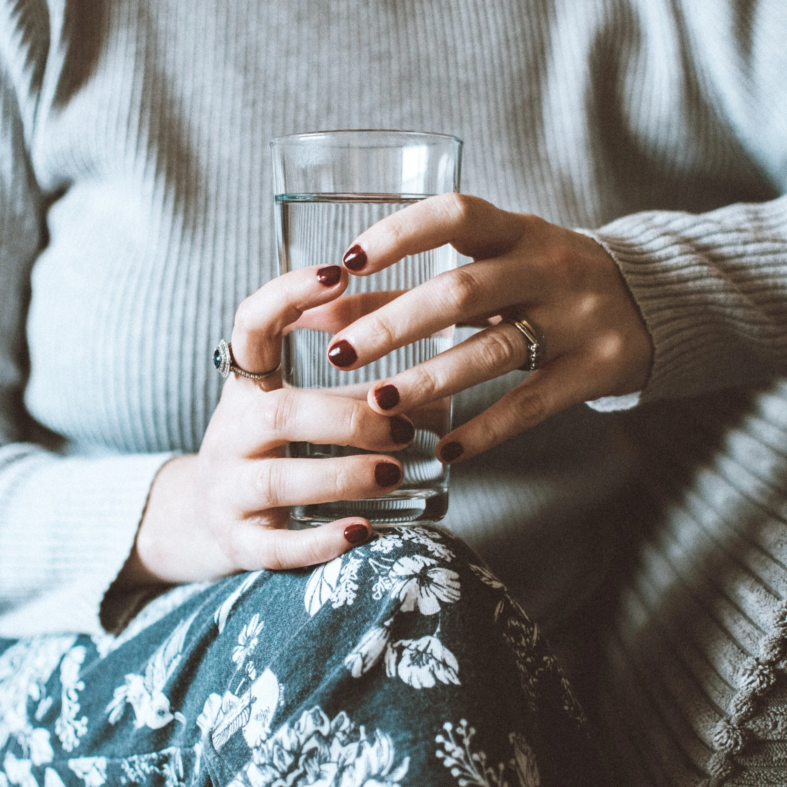 Woman's hands holding a tall glass of water.