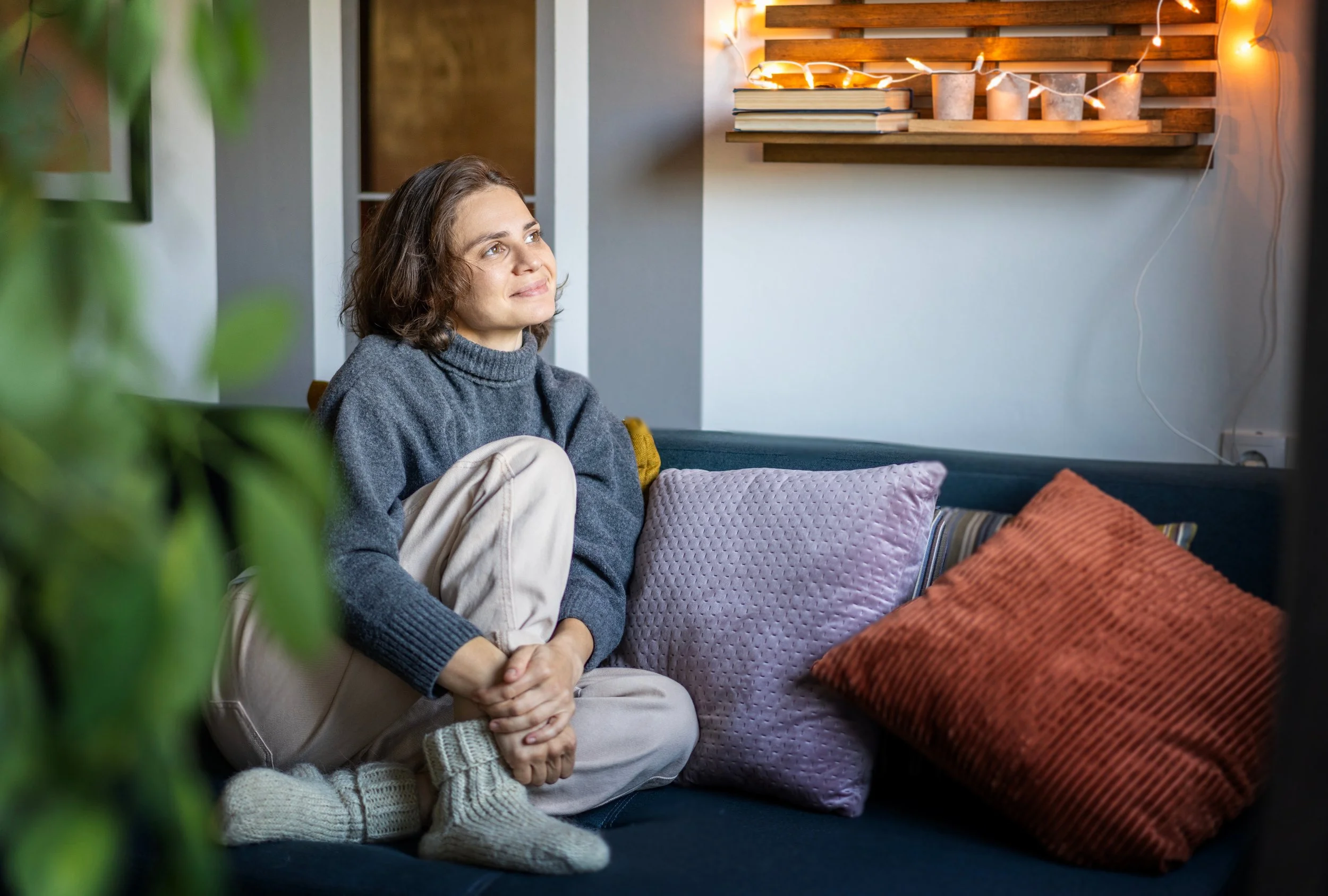 Woman sitting thoughtfully on a couch reflecting on personal growth and emotional healing.