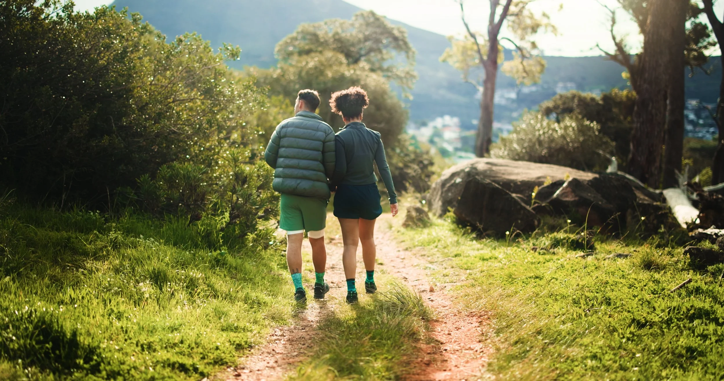 Couple walking together on a wooded trail in early spring light, representing trust building and consistent relationship effort