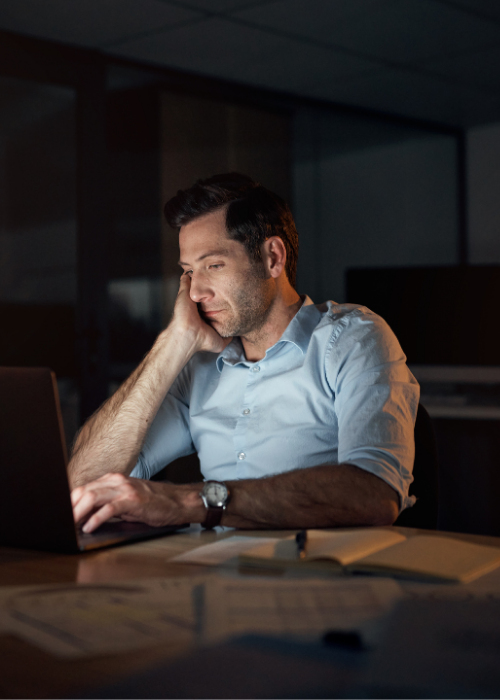 Man working late on a laptop showing signs of burnout
