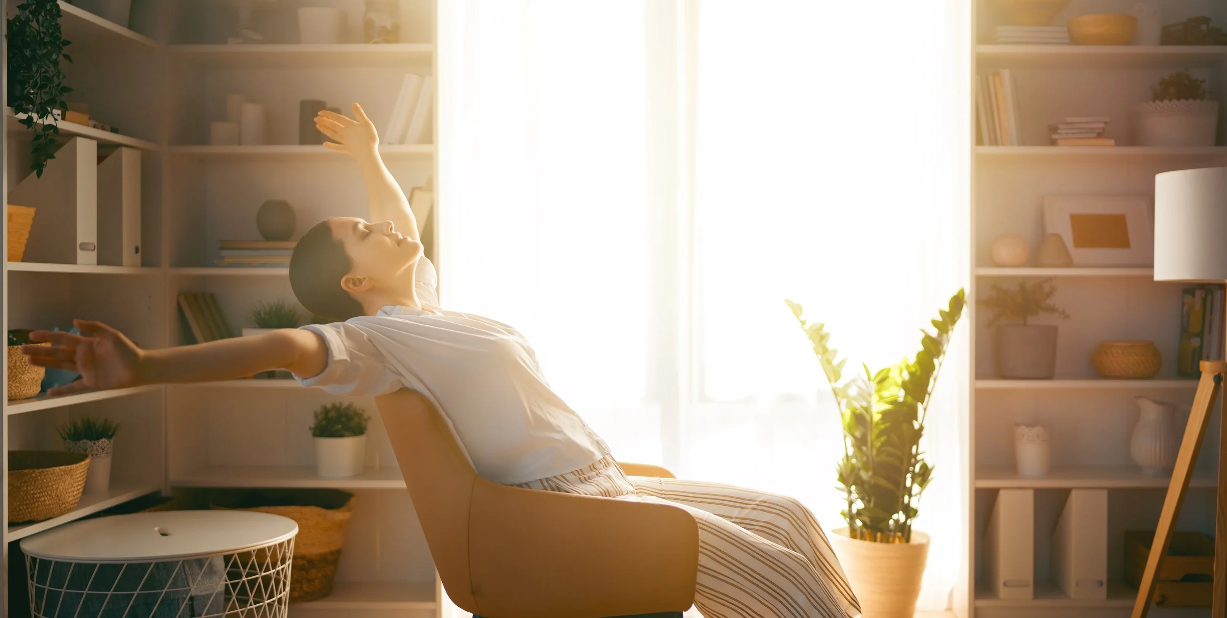 Woman relaxing with open arms in sunlit living room, feeling relief from burnout and overwhelm—individual therapy for women at Sacred Healing Counseling, Central Florida and online