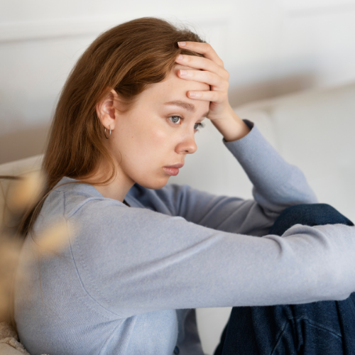 Woman sitting with her hand on her forehead showing signs of stress