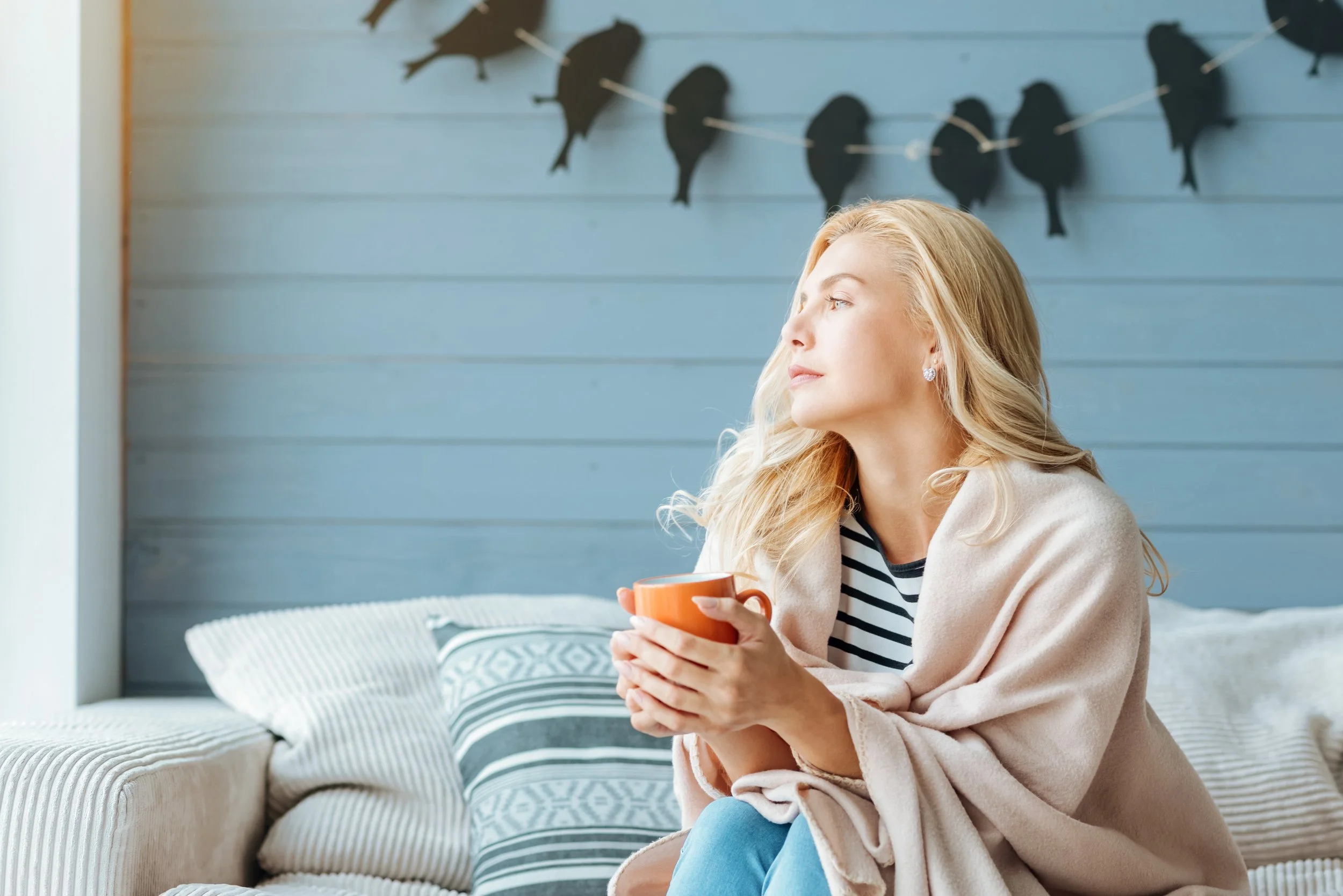Woman reflecting near window during online therapy session about burnout in Florida.