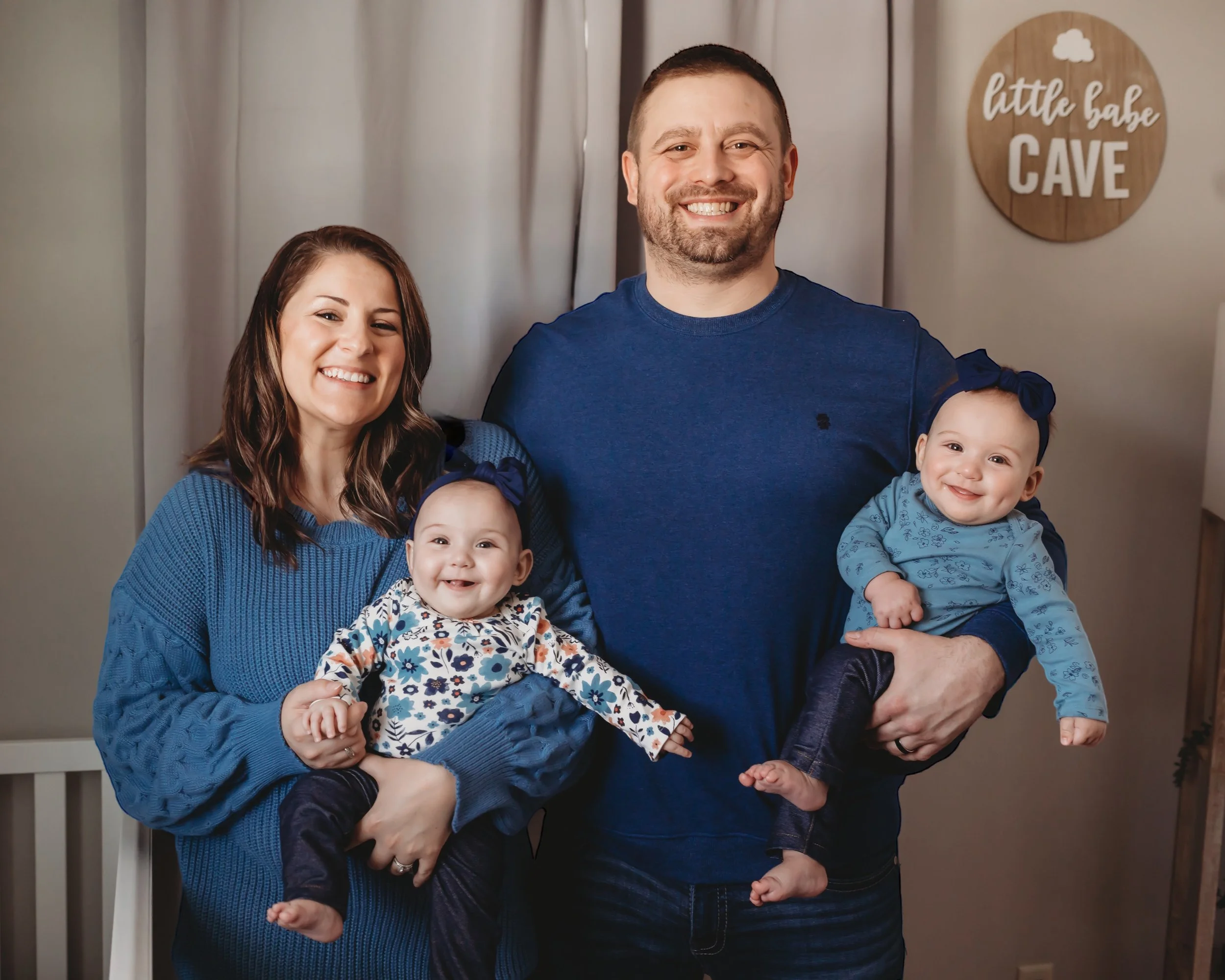 A joyful mother and father, each holding a smiling baby, posed for a portrait.