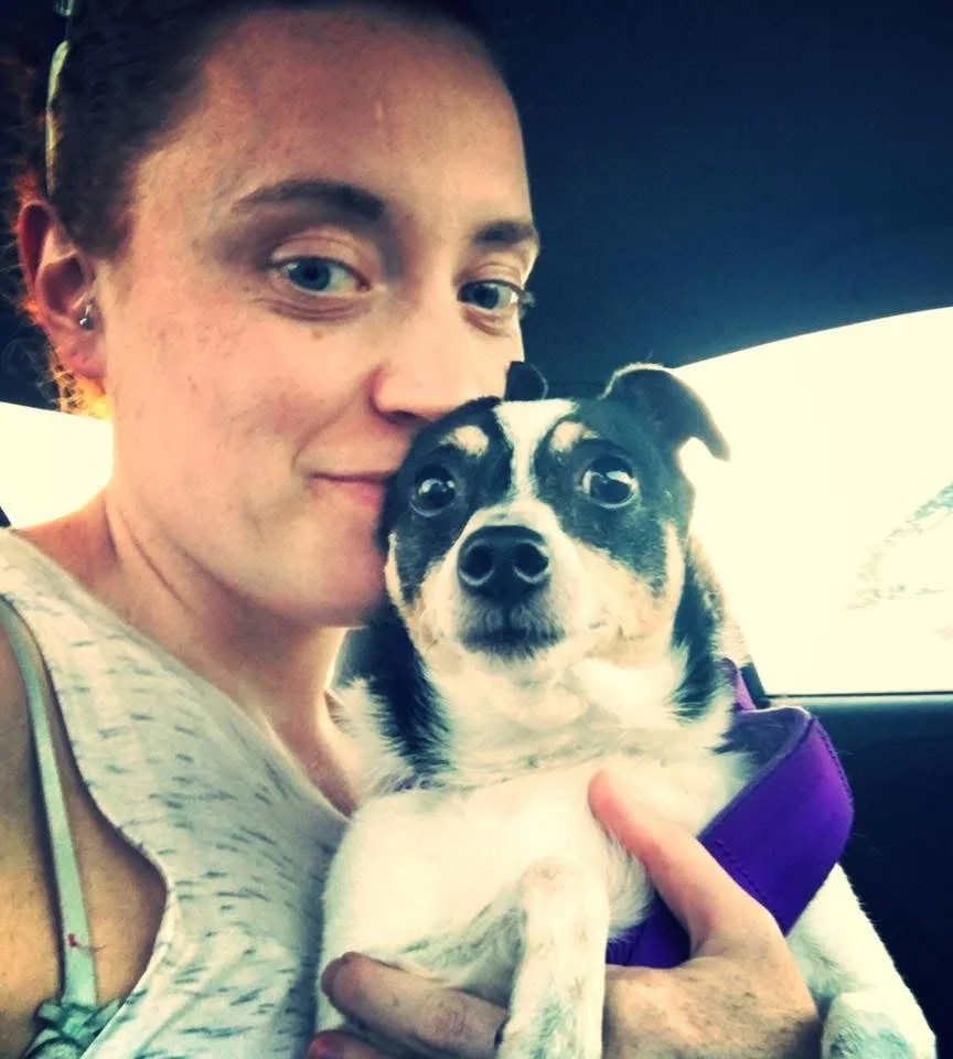 Steph, looking at the camera, holding her dog Chico