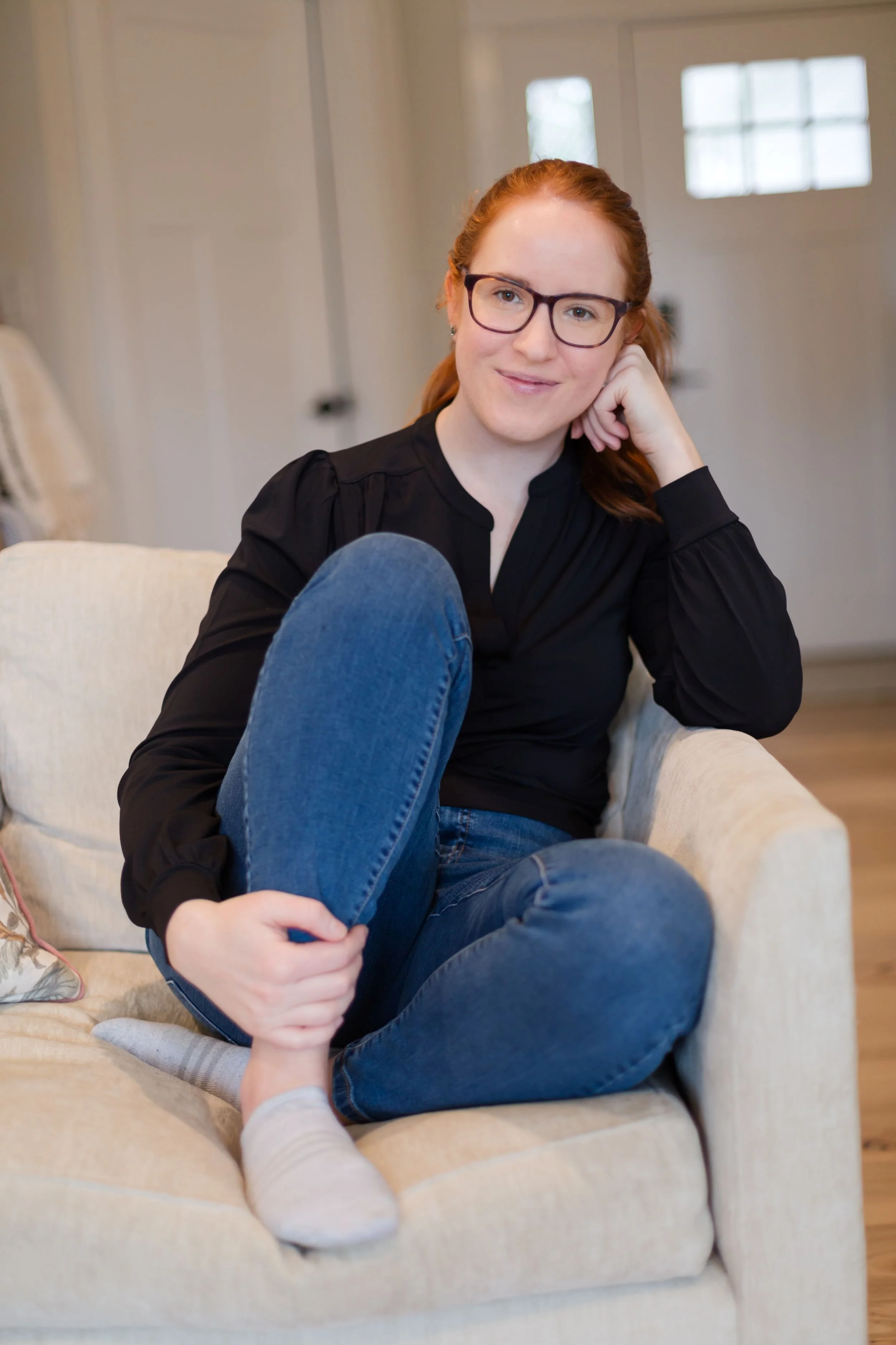 Katie Ebermen, founder of Simply by Katie, sitting comfortably in a chair. She is an Edmonton website designer who creates story-driven Squarespace brands for women building a life of their dreams.