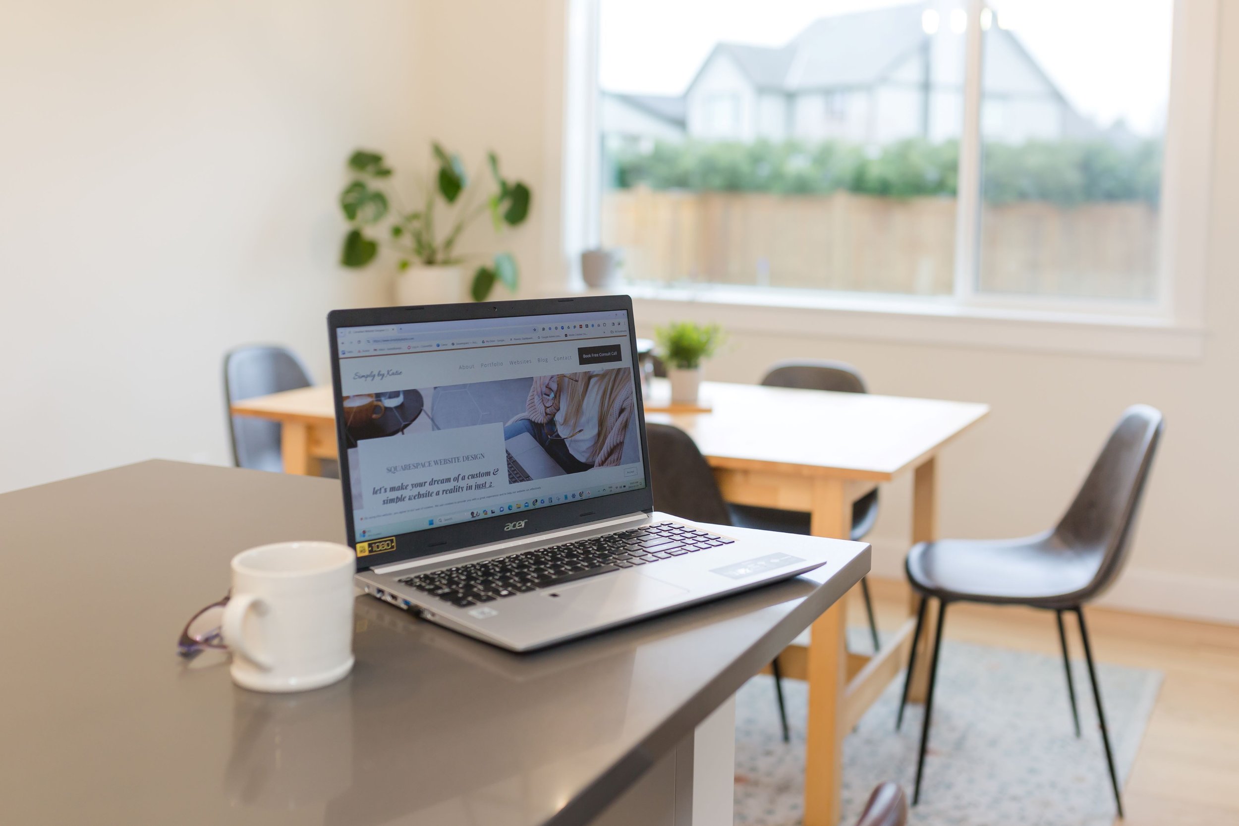A laptop on a bright kitchen counter with soft natural light, representing creativity, connection, and joining the Simply by Katie community for women in business.