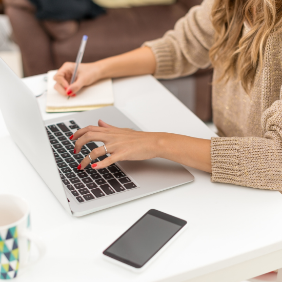 Close up of a woman writing notes and working on a laptop, illustrating the intentional strategy Simply by Katie uses to build next-level websites for Edmonton women in business.