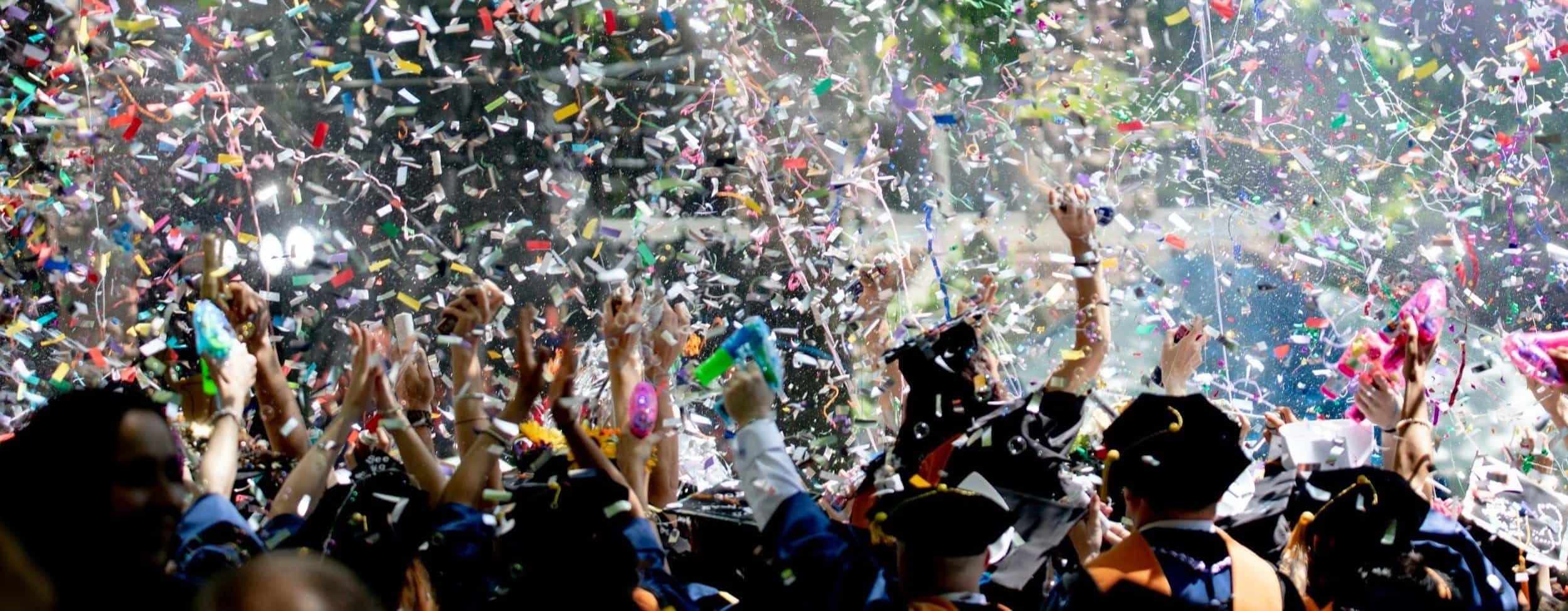 Joyful alumni celebrating whilst throwing confetti. Representing an engaged and happy alumni community.