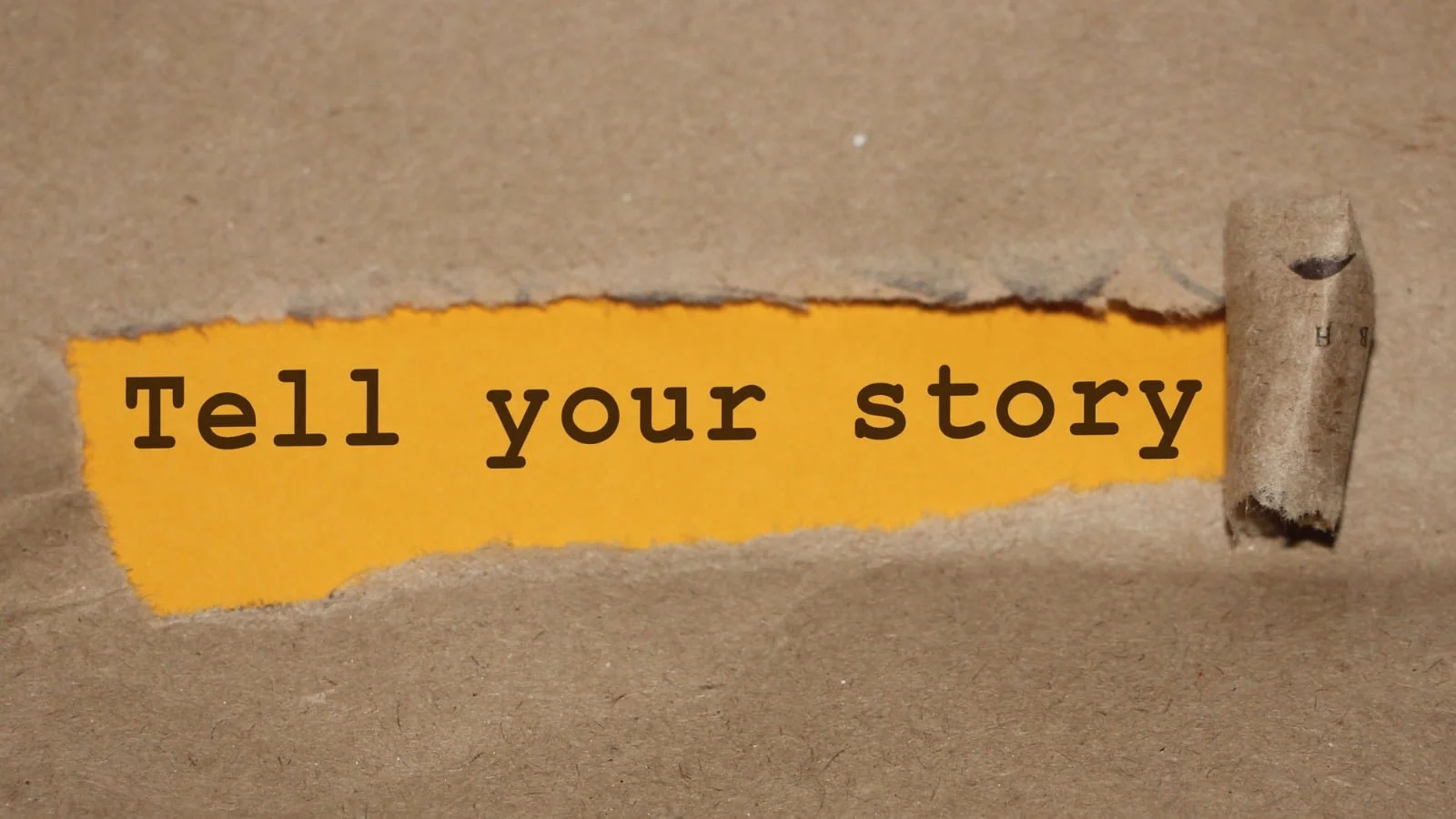 School storytelling: Brown paper with a section ripped in the middle with the text 'Tell your story'