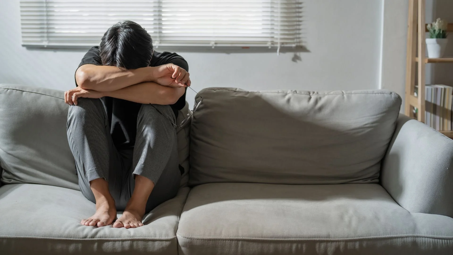 Sad Asian male sitting alone, illustrating a mental health problem such as depression or one of the common types of anxiety disorders like social anxiety or generalized anxiety.