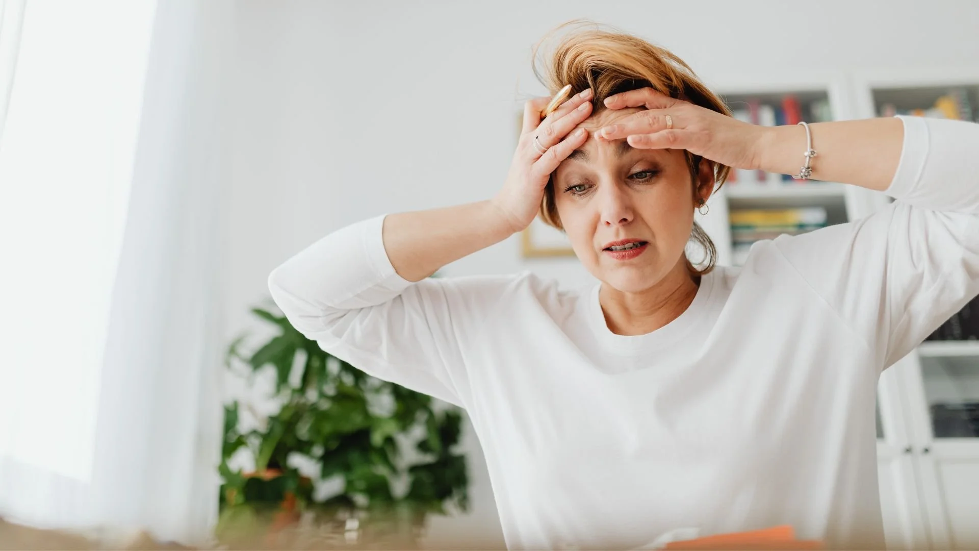 Worried woman holding her hands on her forehead while experiencing symptoms of separation anxiety in adults.