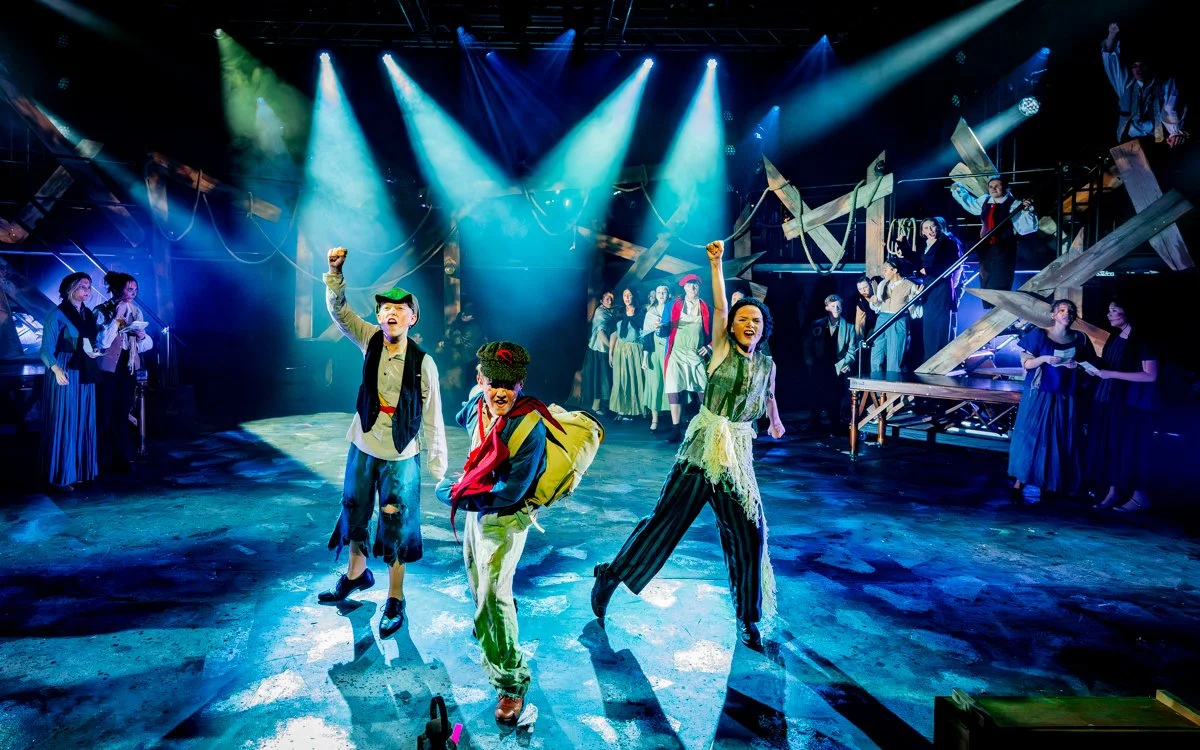 Actors on stage performing in a theatrical production with colorful costumes and dramatic lighting.