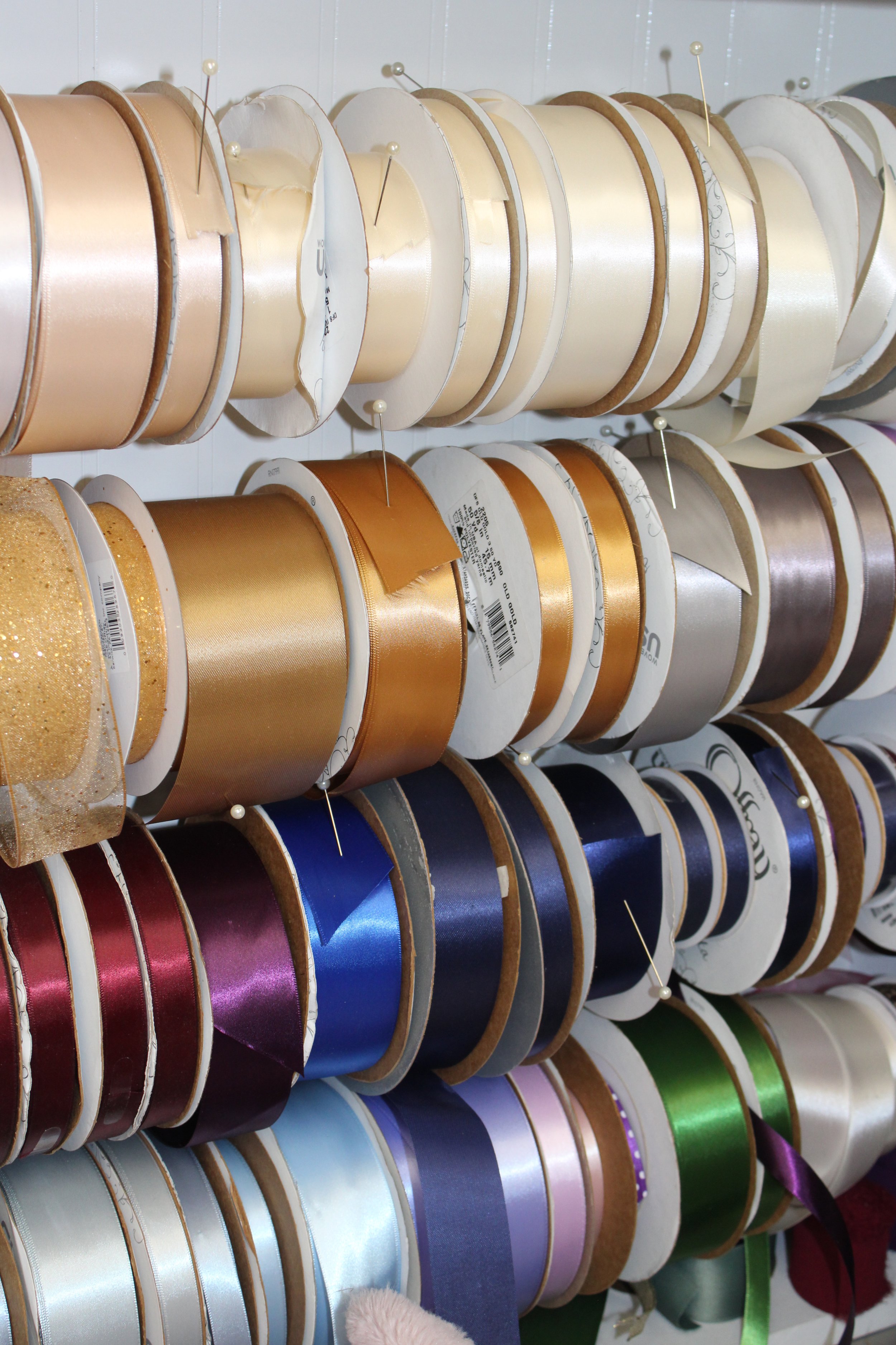 Assorted rolls of colorful satin ribbons on display rack