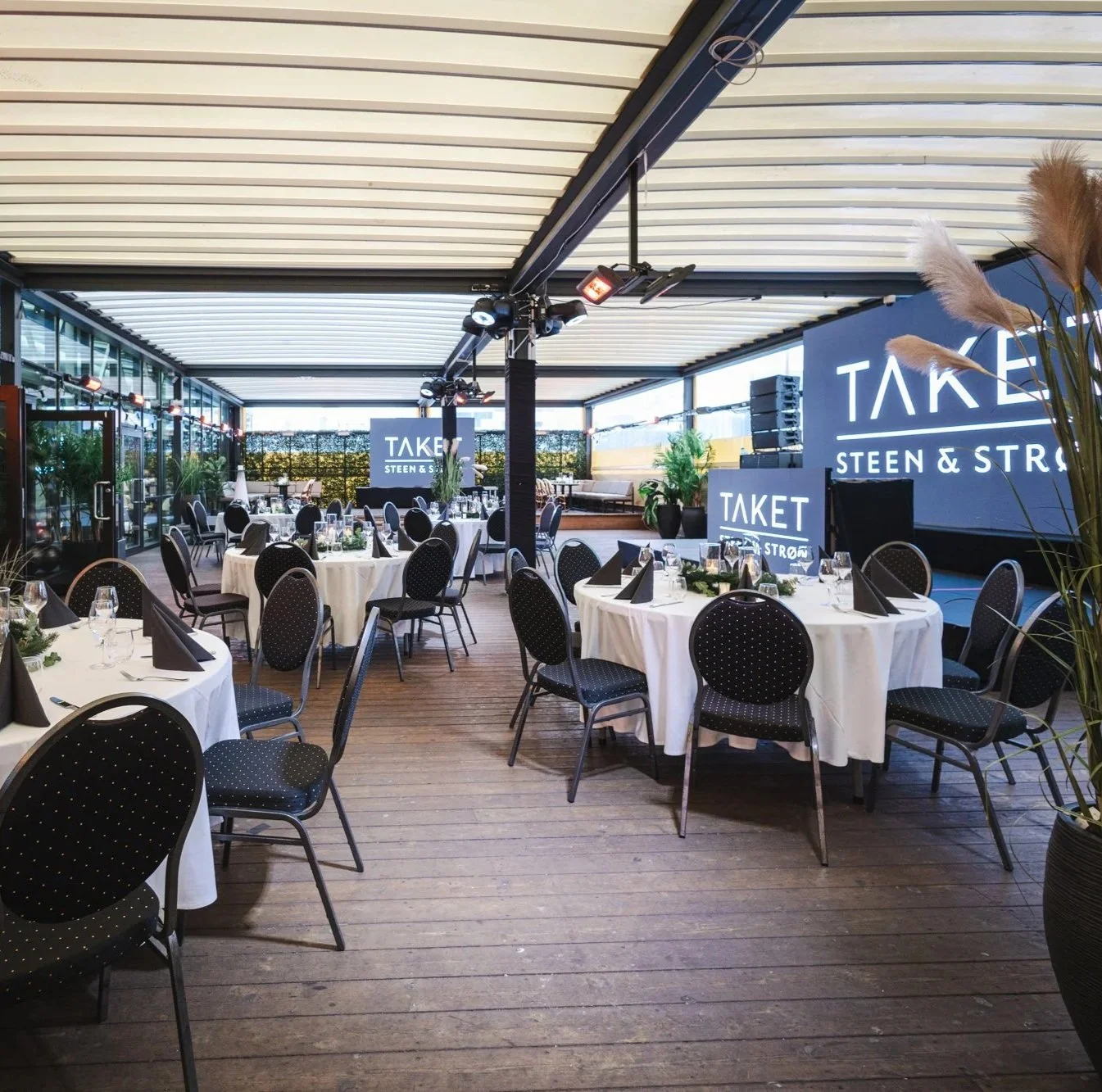 Bilde av dekket bord med lys, julepynt og hvit duk på takterrassen, hovedlokalet på TAKET Steen og Strøm Oslo