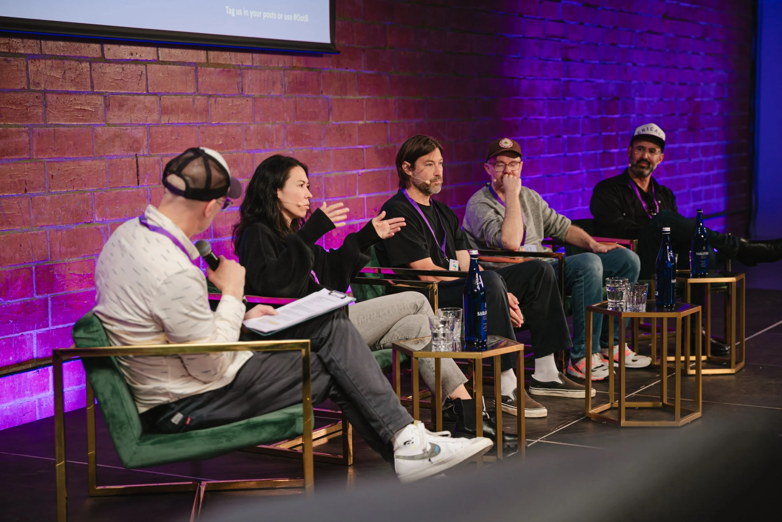 Five talk panel members in discussion while sat and looking at each other during an event