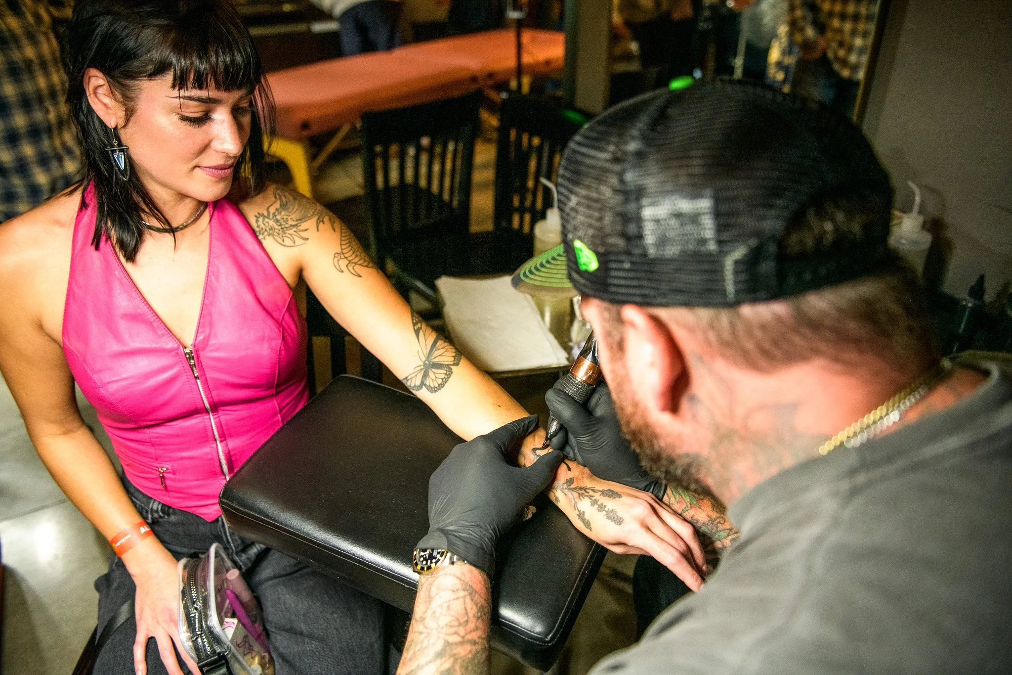 Lady in a pink top getting a tattoo on her forearm during an event at Bike Shed Moto LA