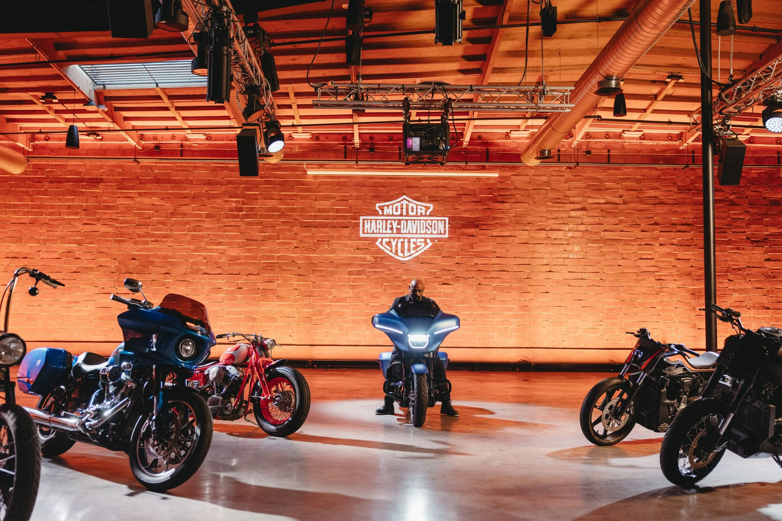 Man sitting on a Harley Davidson motorcycle in an event space during an event