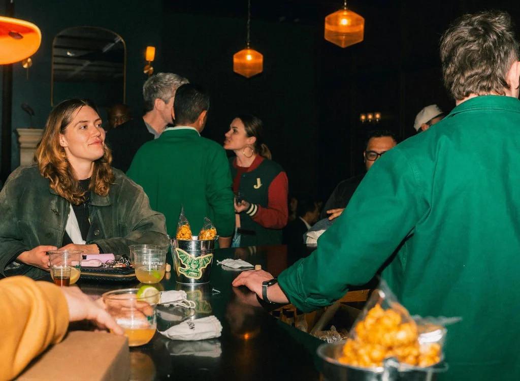 Candid photo of guests of an event enjoying bar snacks and drinks while smiling