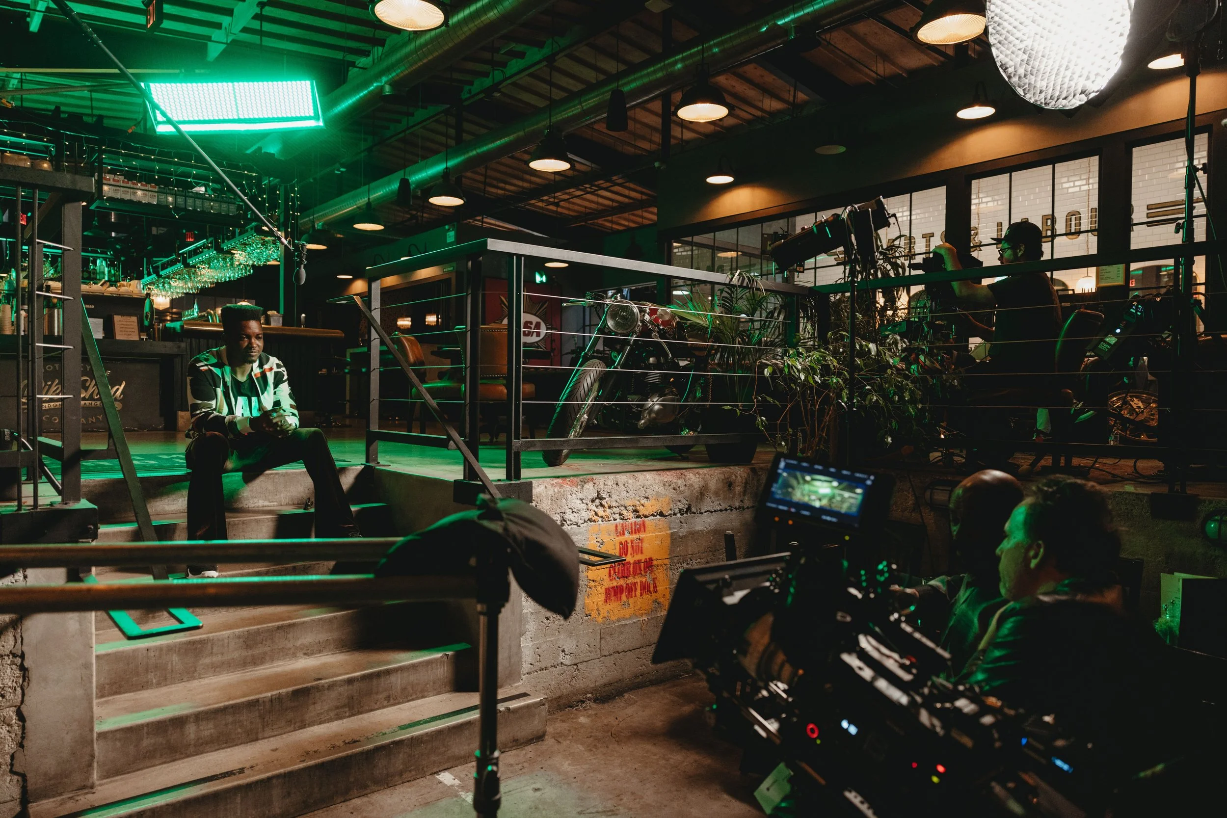 Moody scene of a man sitting on some steps talking to camera for an event at Bike Shed Moto LA