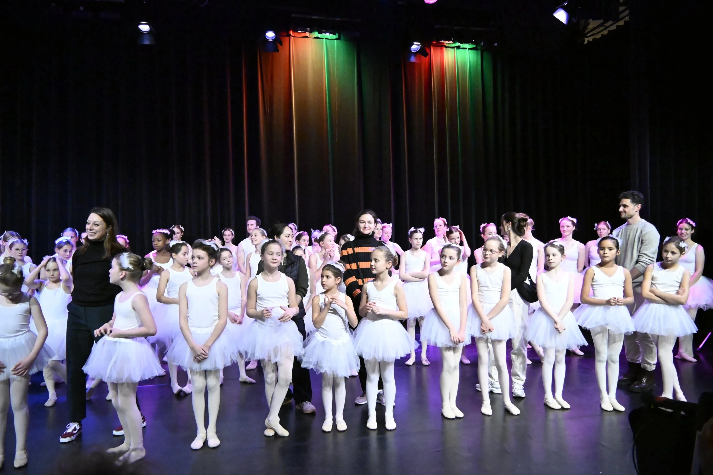 vier docenten tussen heel veel jonge dansers in een witte tutu