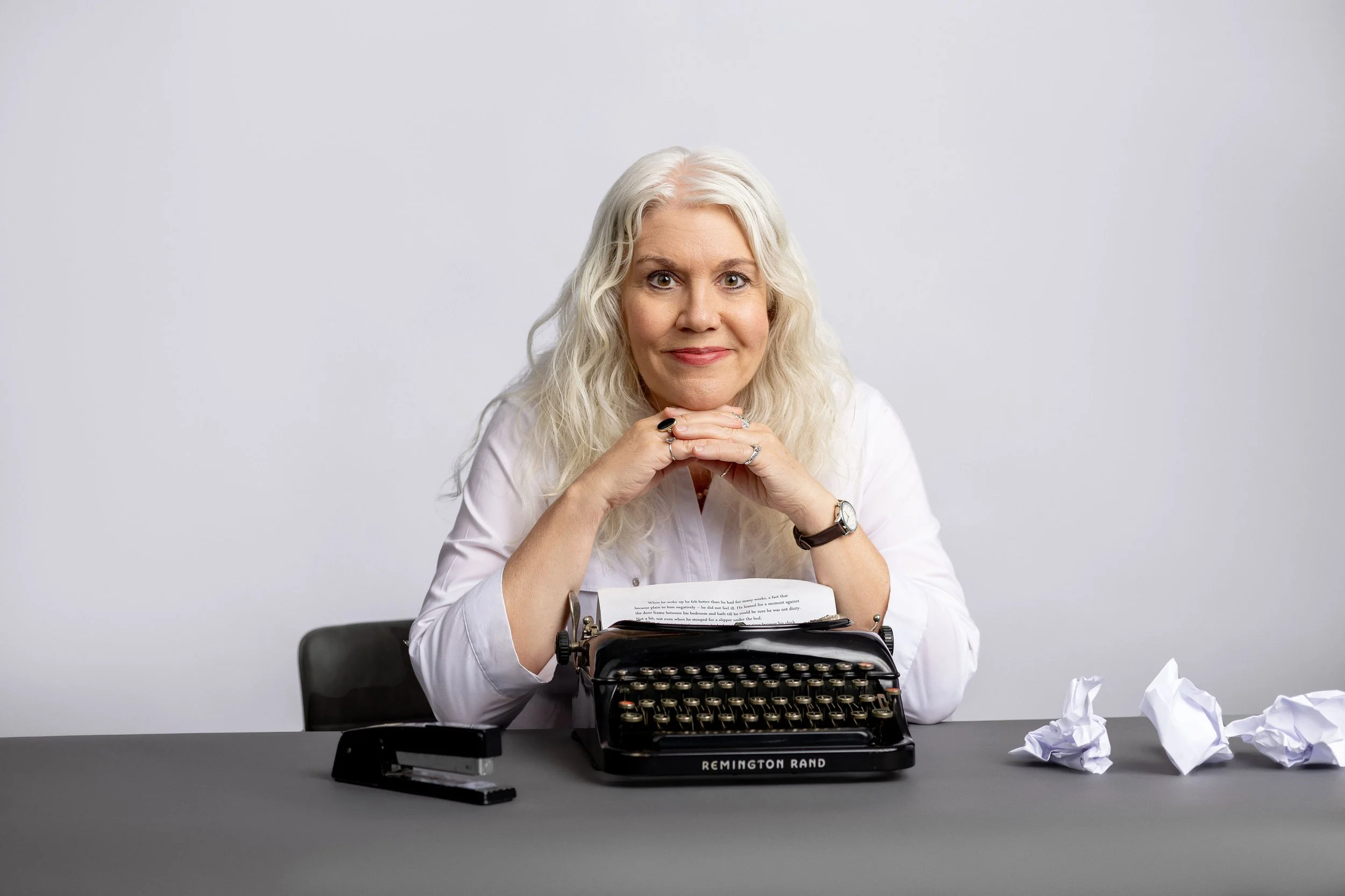 Author Gina Malone smiling with a vintage typewriter, discussing her new chapbook and creative expression.