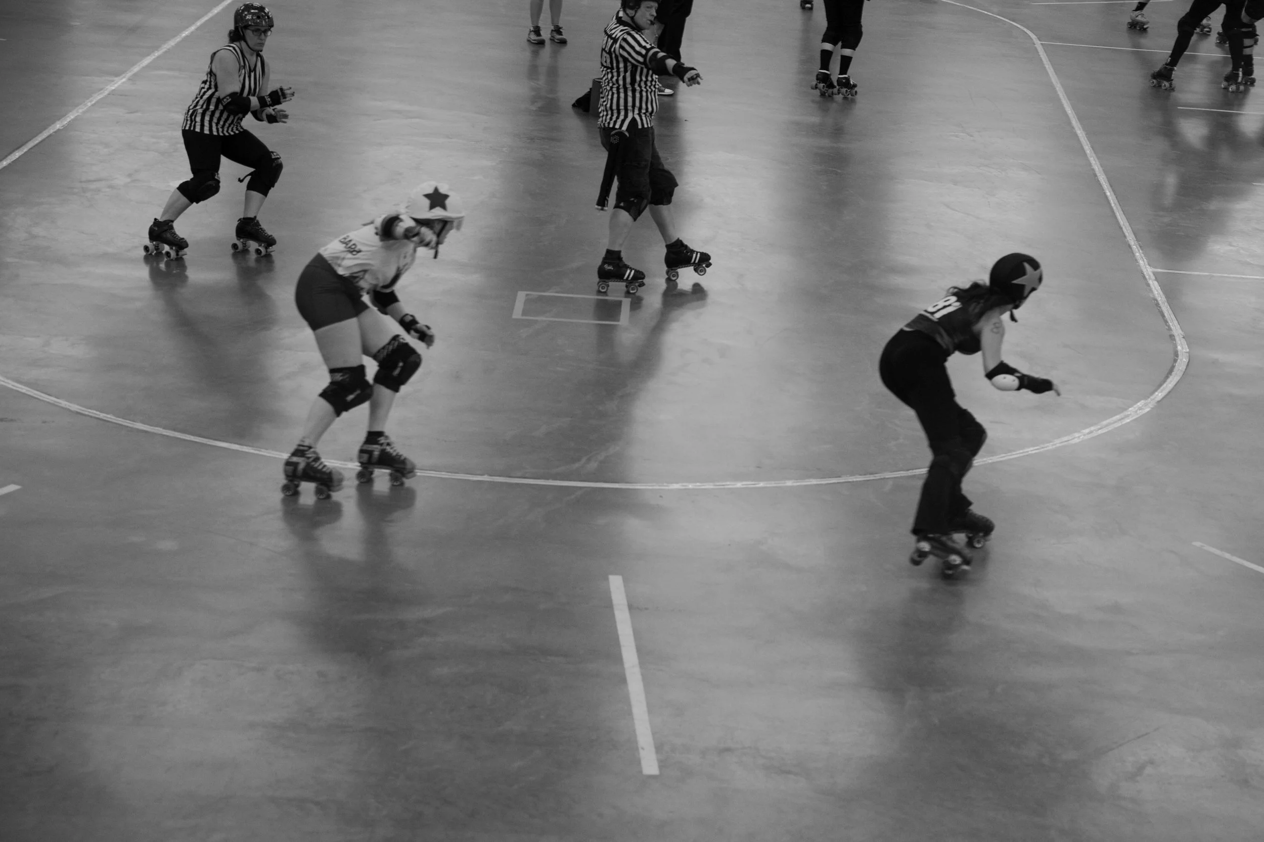 Black and white photo of two jammers racing around the track, one leading the other in a high-energy scene captured in Victoria BC.