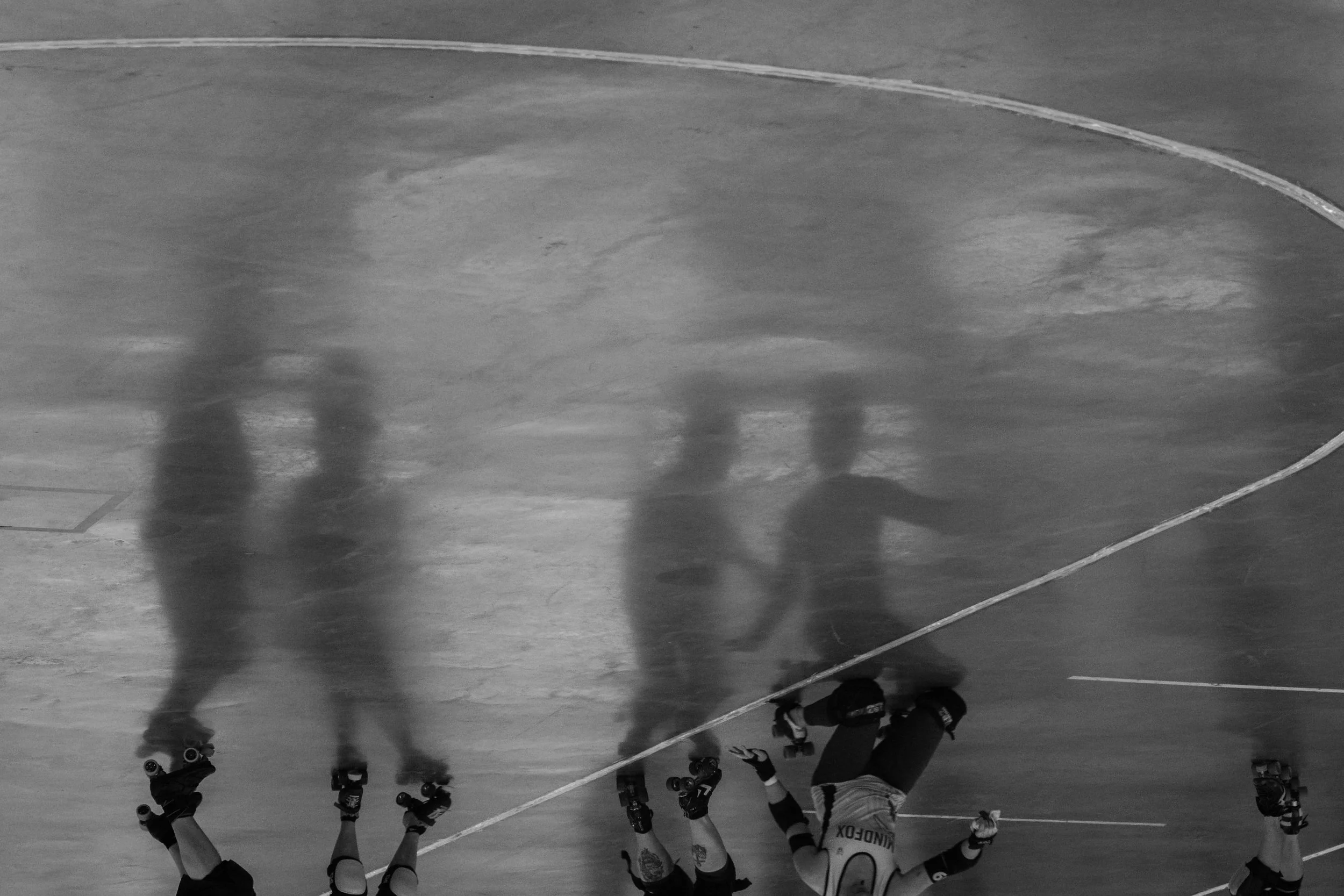Black and white image focusing on the shadows of skaters moving across the track, captured in an artistic Victoria BC photography style