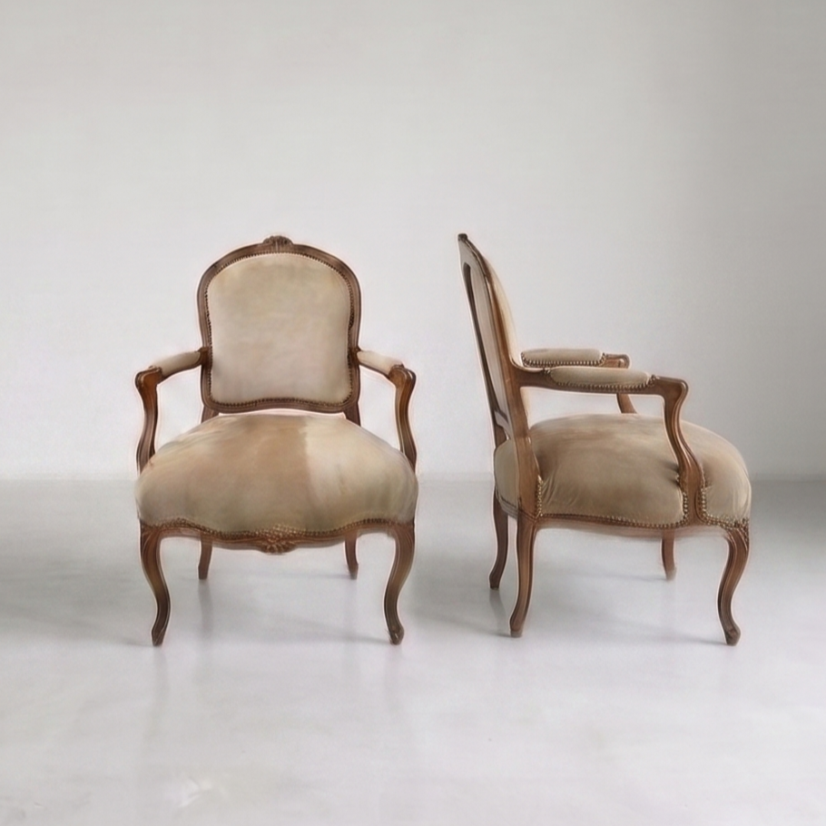 Carved Louis XV style walnut fauteuils, upholstered in the 21st century in camel-colored suede.  Well restored (details in description).  Circa 1860-1880.  Beautiful matched pair.  Original construction, strong but super comfortable. Excellent condit
