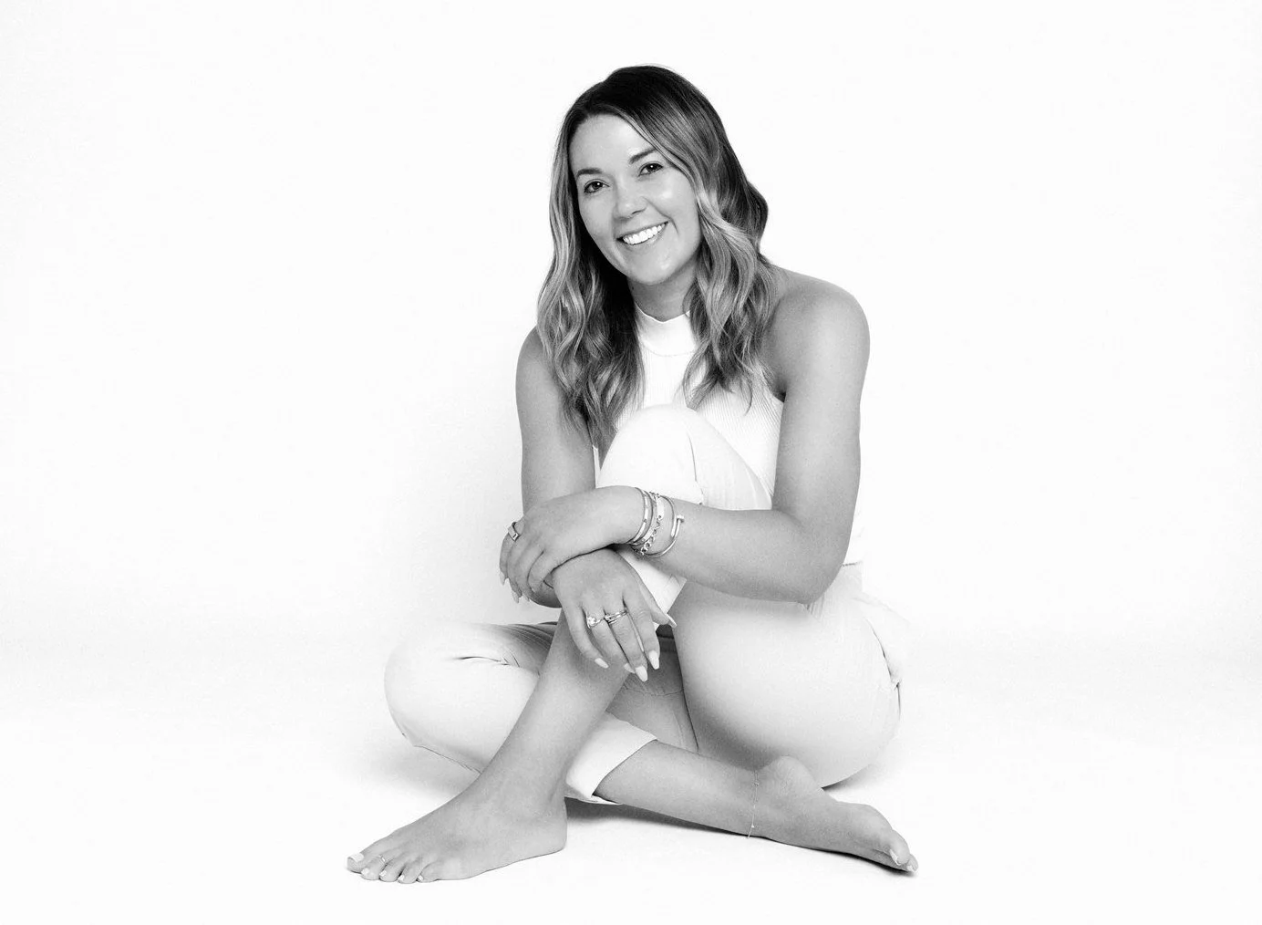 Megan Walerius seated in an all-white outfit for a portrait on her official website