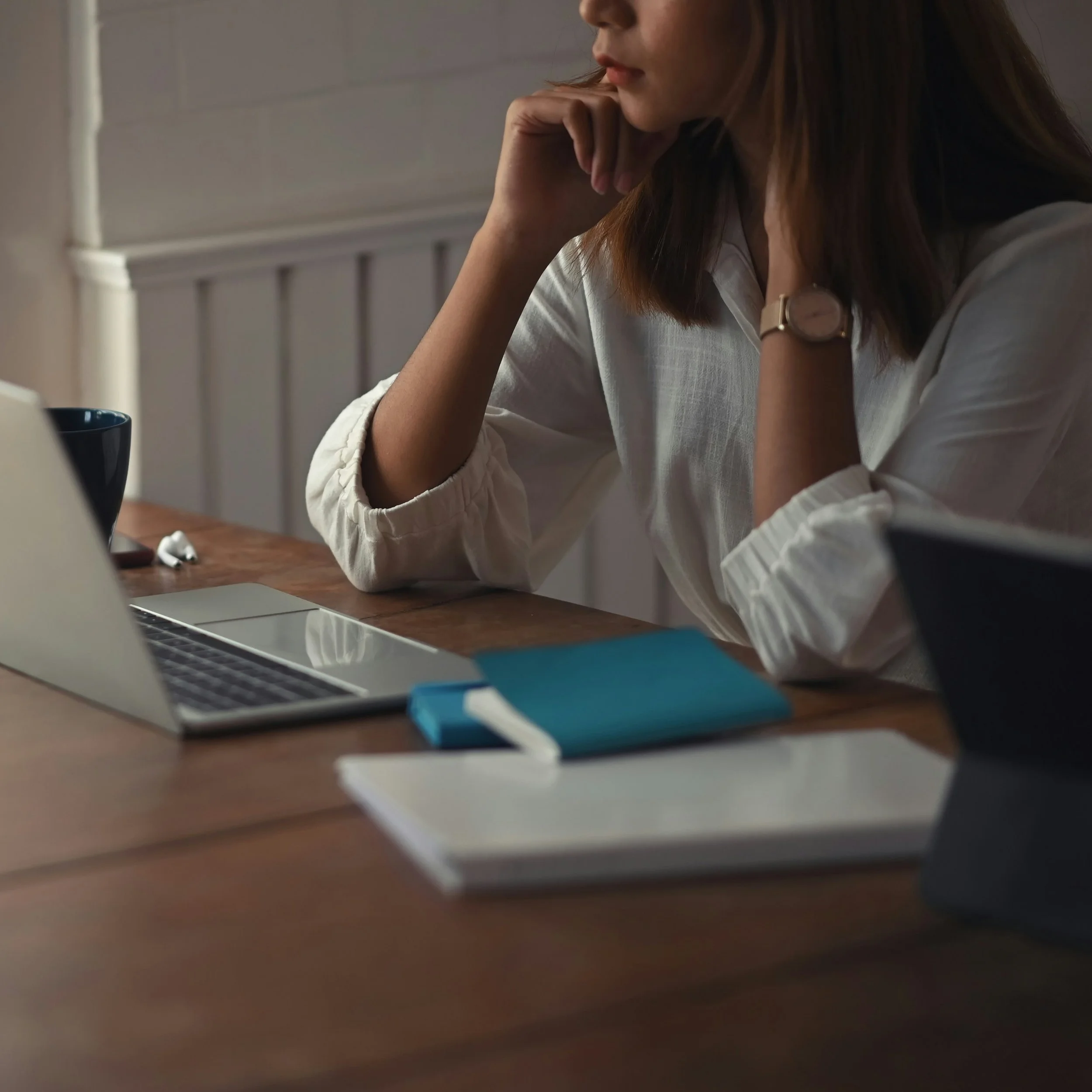Image of a woman sitting at a table with a journal and laptop.