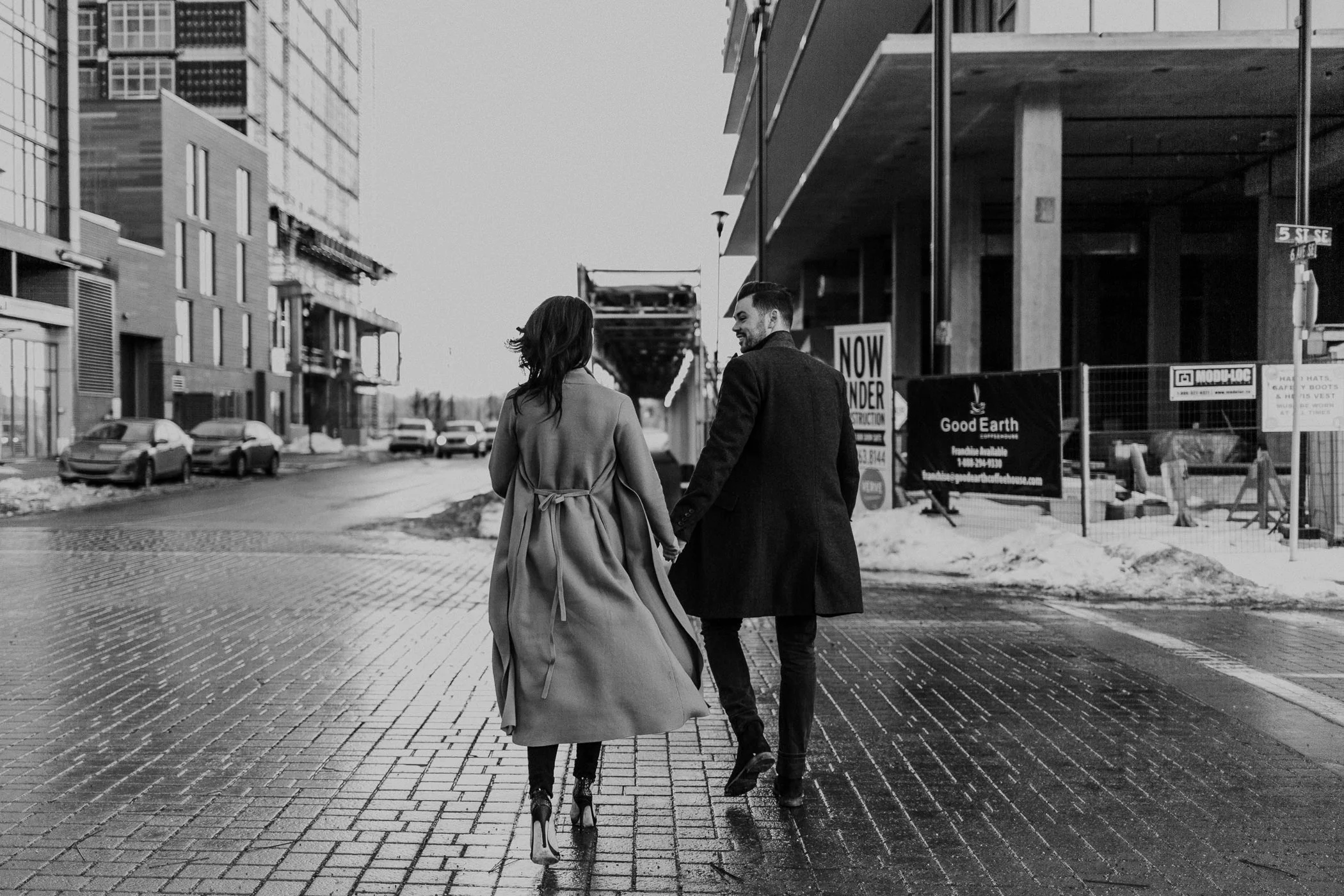 black and white photo of glamorous couple crossing the street ini a trench coat 