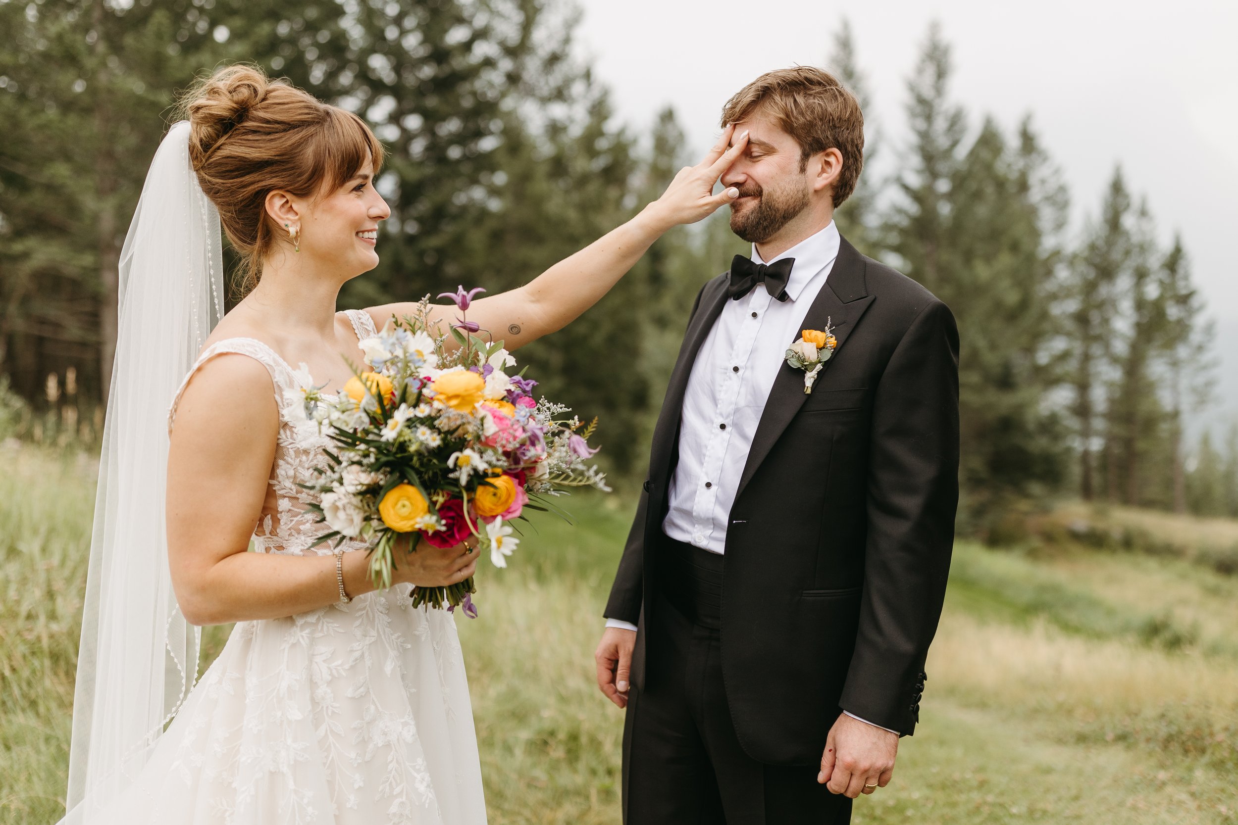 Candid photo of bride with bright, modern bouquet at their wedding at Silvertip Resort in Canmore