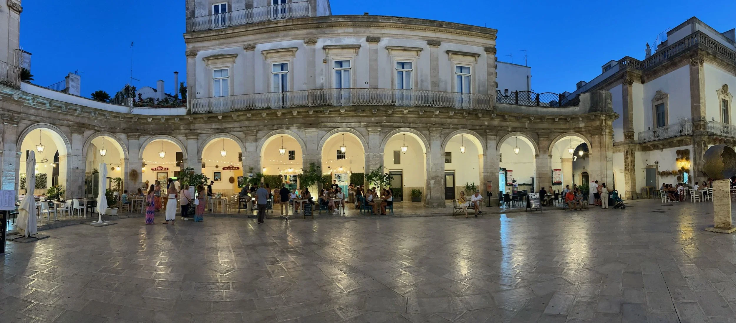 This is the elegant Piazza delle Libertà in Ostuni, Apulia, Italy. Ostuni comes alive after dark, with its authentic Italian charm undiluted by tourist crowds. Stroll whitewashed alleys, pop into local bars tucked behind ancient doorways  and experie
