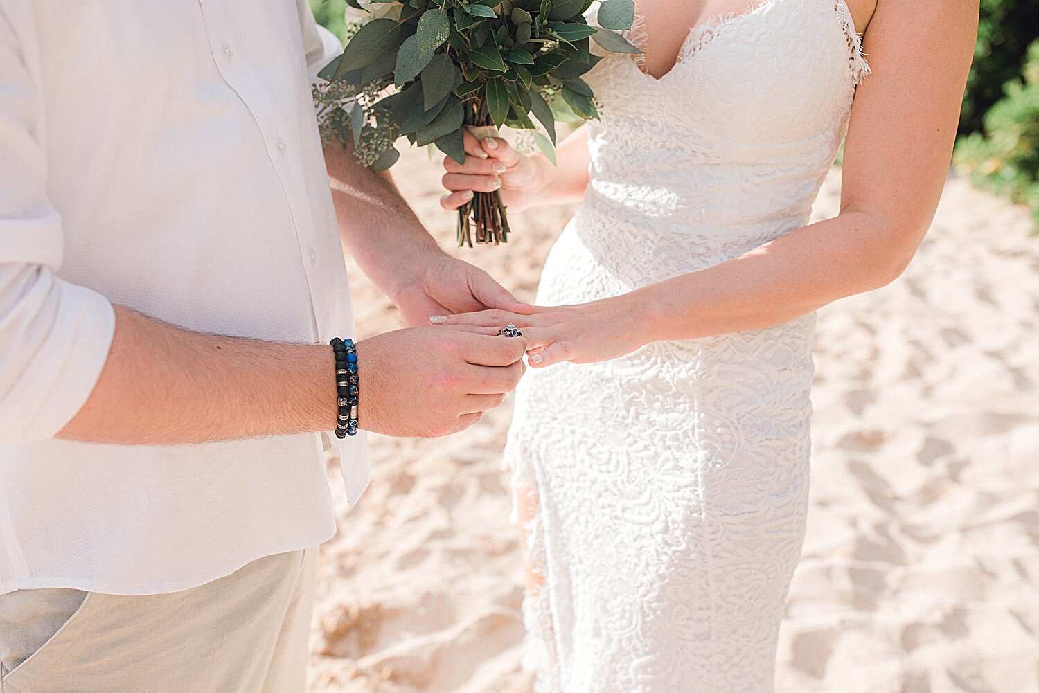 Groom putting on the bride's ring during Maui beach elopement