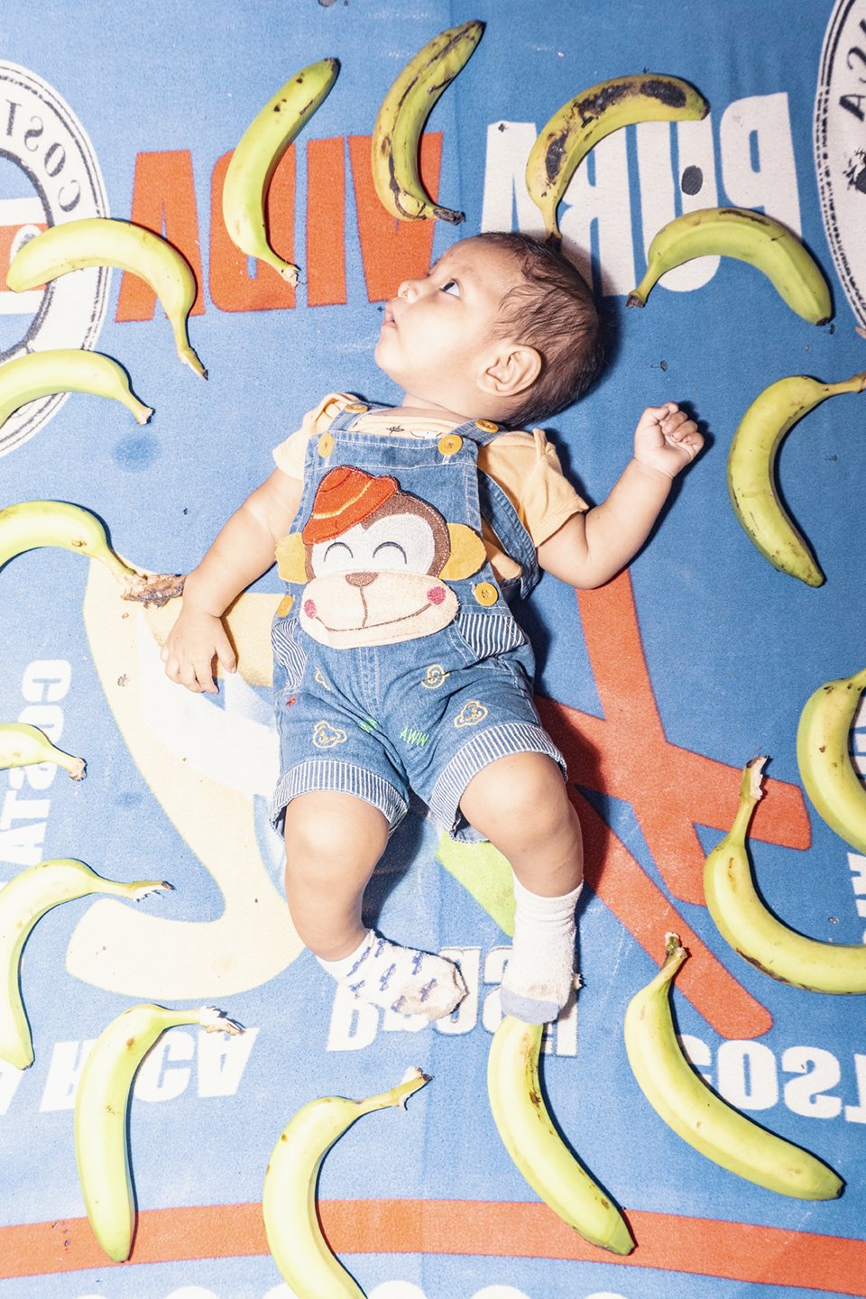 Six-month-old Dylan Lorenzo lies in a bed pedestal with bananas arranged by his mother, Dylan had been hospitalized after repeated respiratory complications, while his family mourns the recent death of his four-year-old cousin, a child who spent days