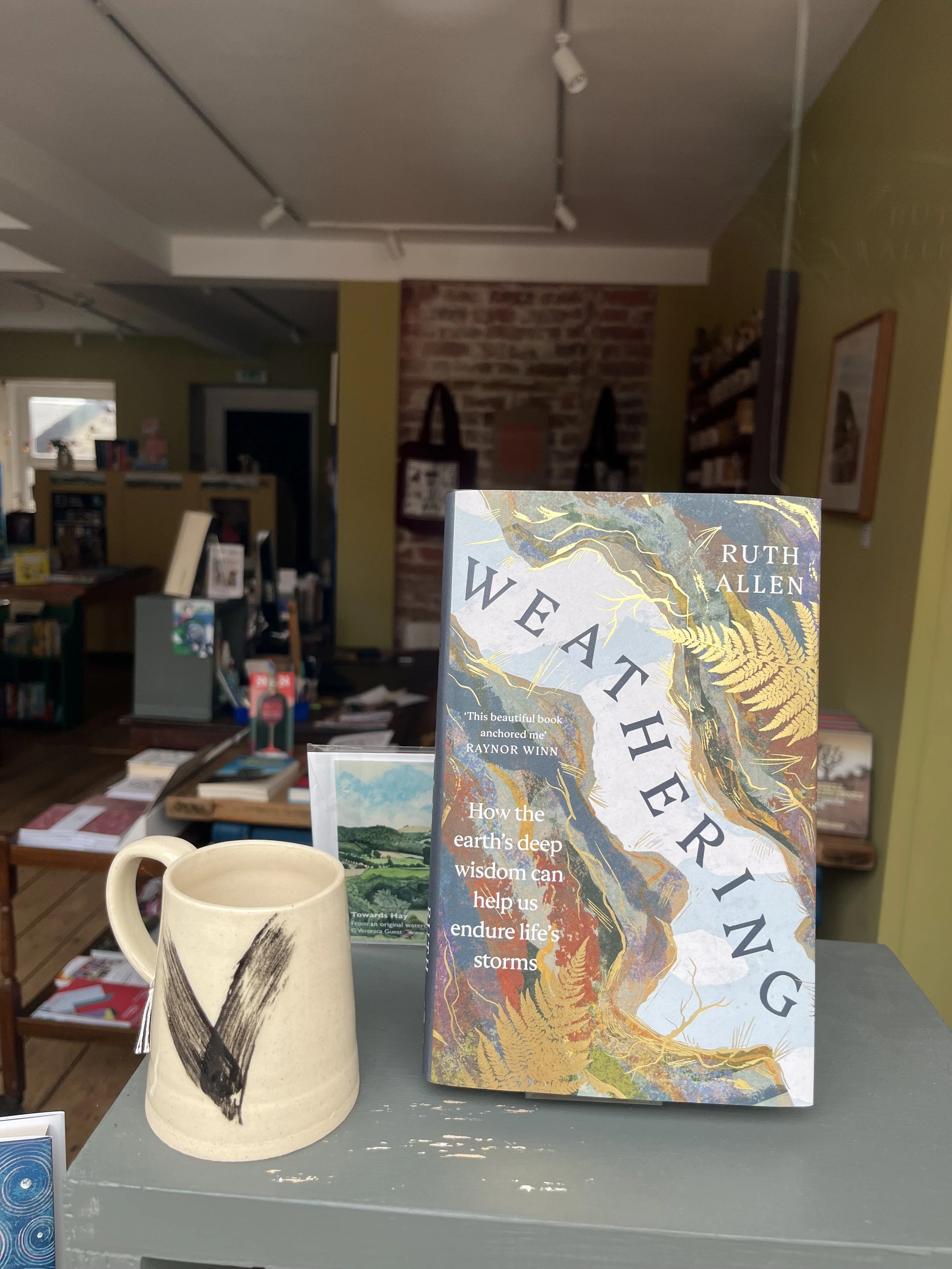 A bookshop display at North Books, featuring 'Weathering' by Ruth Allen and a hand made ceramic mug.