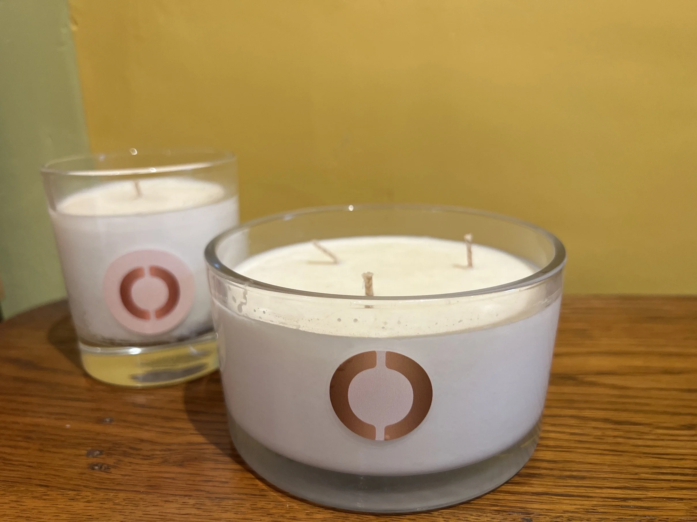 Two hand made white candles in clear glass holders.