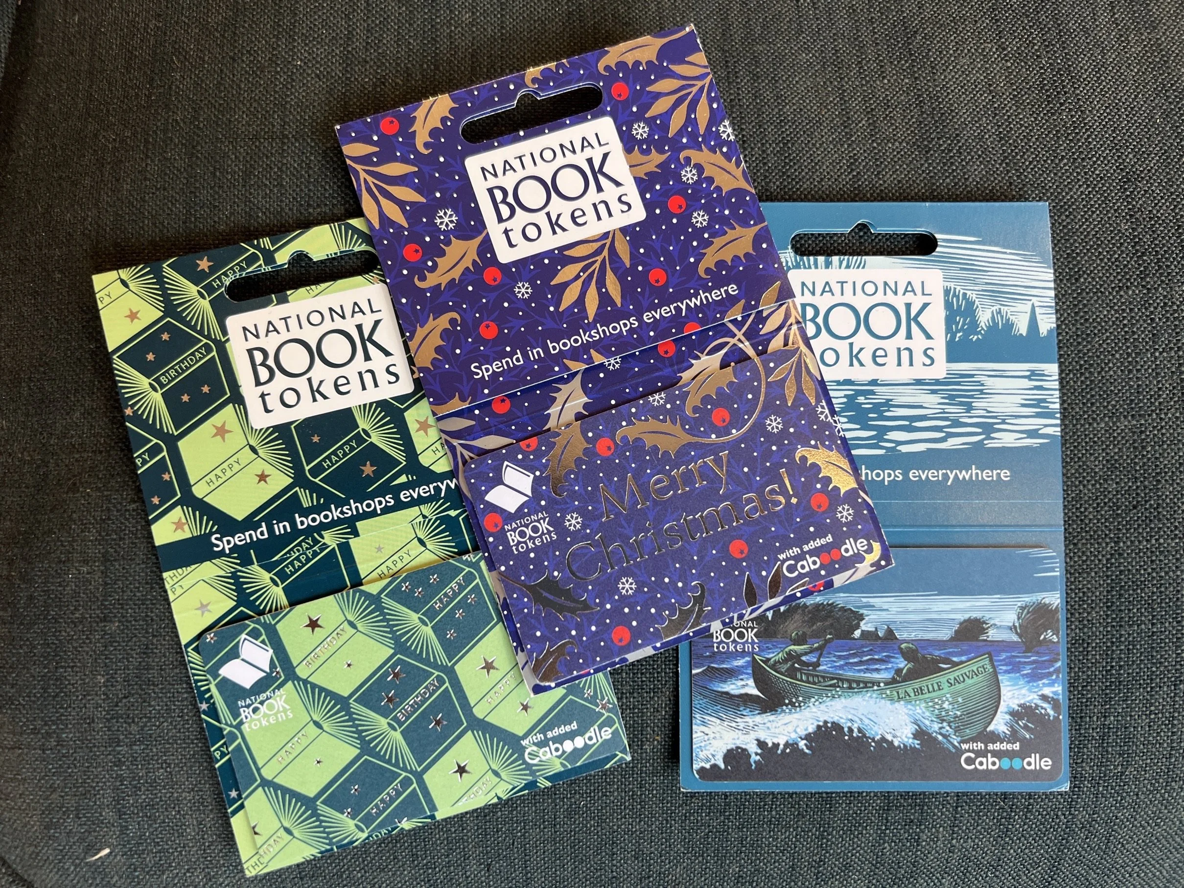 Three National Book Tokens gift cards with various themed designs.