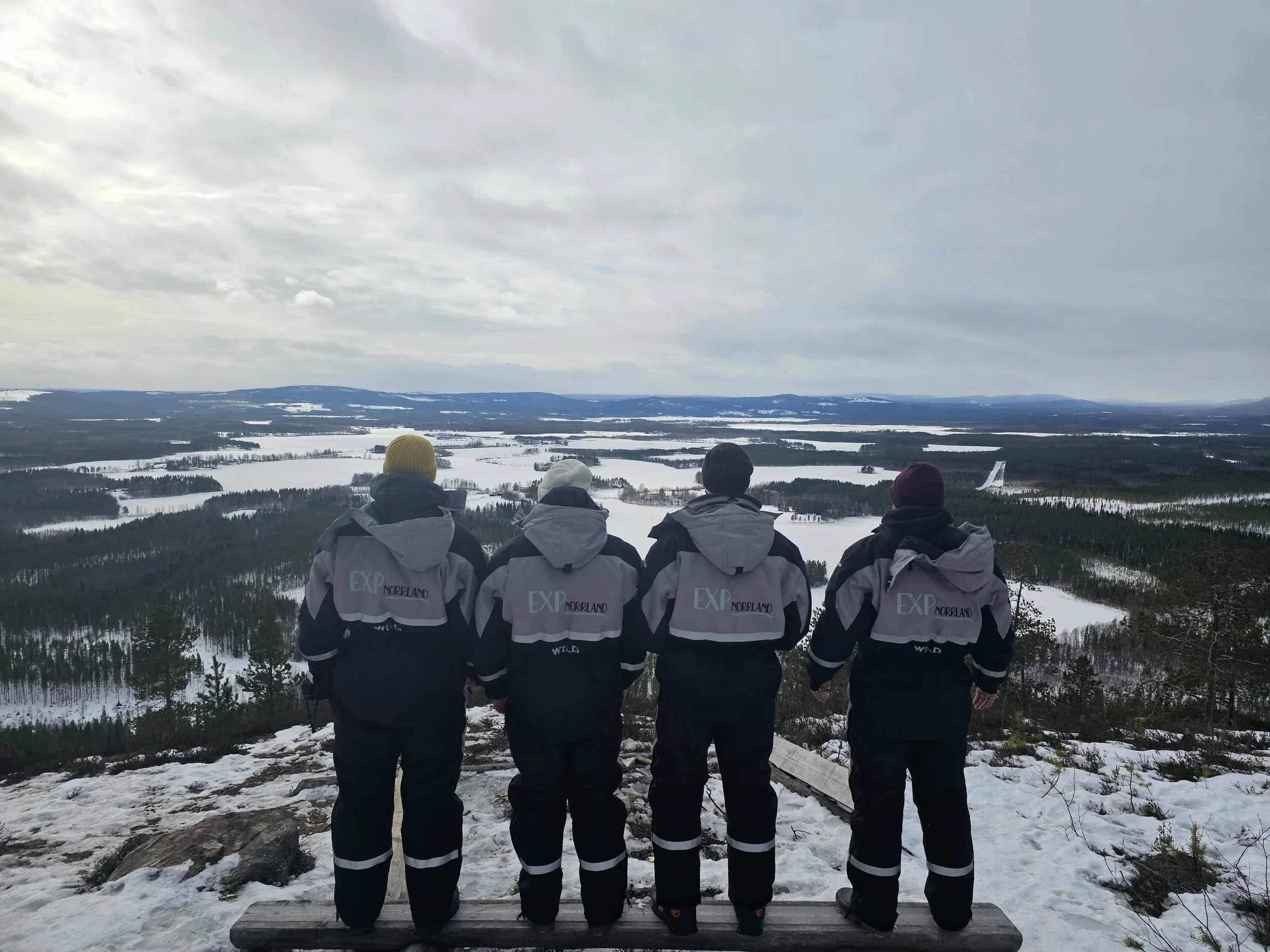 Snowmobile guests enjoying the view of the frozen lakes wearing warm overalls