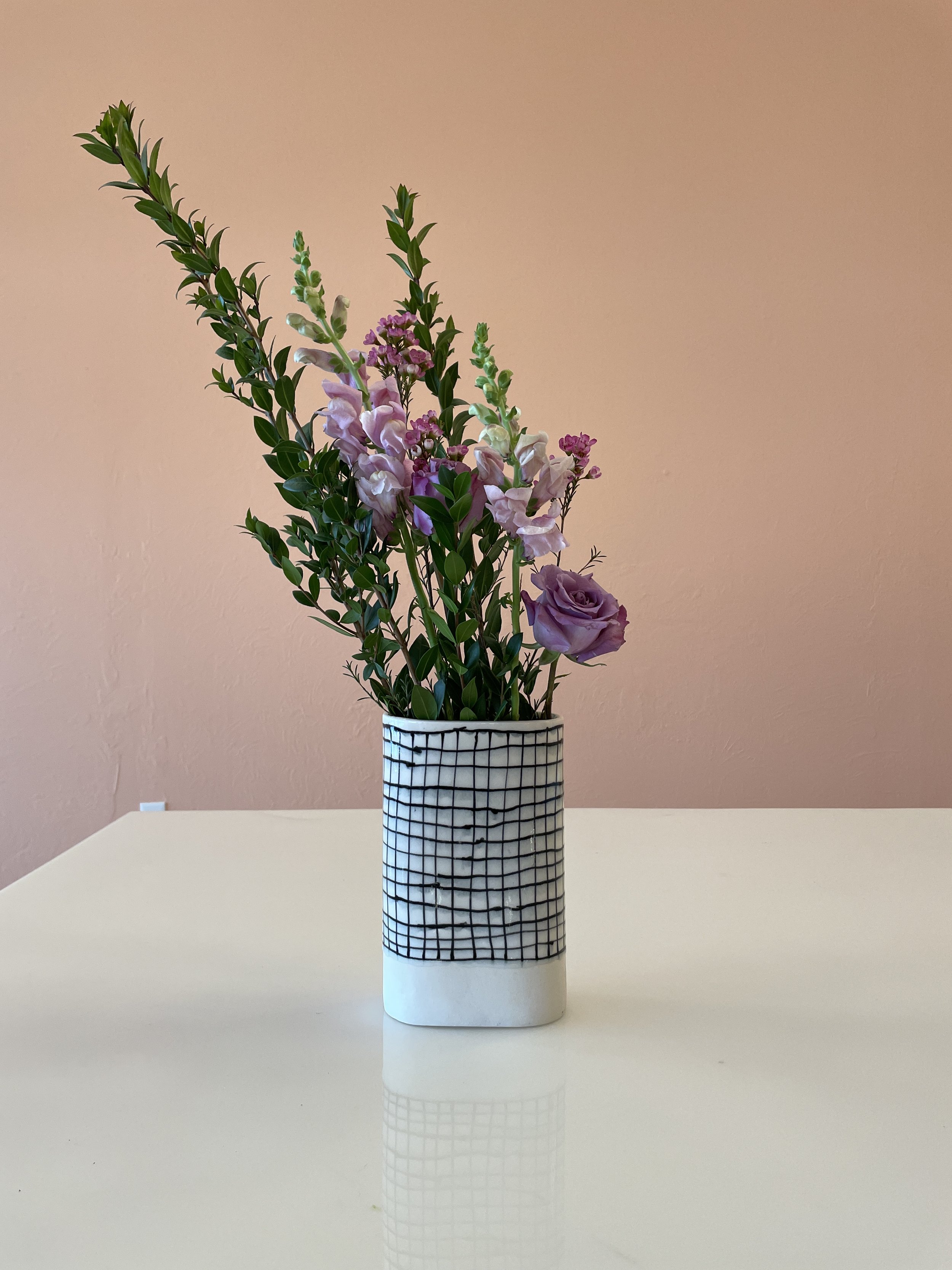  An image of grid patterned ceramic vase with spring flowers in it hand crafted by Lauren HB Studio available for purchase online 