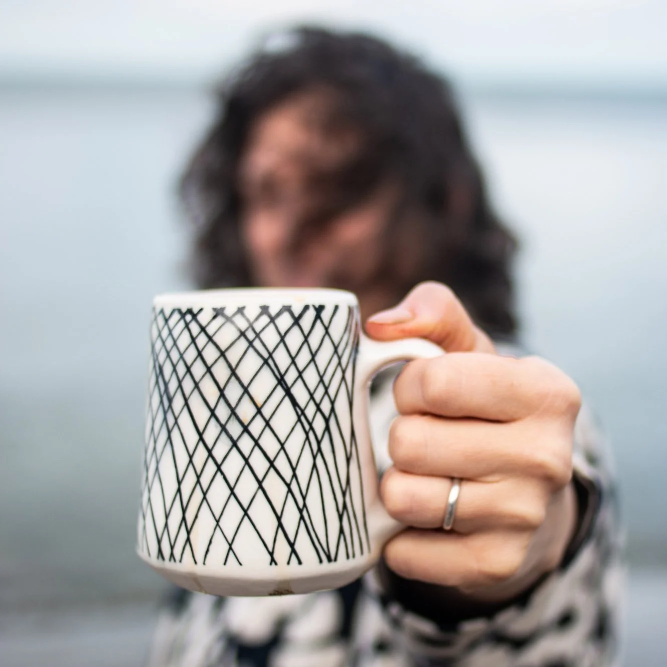 Una imagen de una taza de cerámica blanca con diseños de líneas negras hecha a mano por Lauren HB Studio y disponible para su compra en línea.