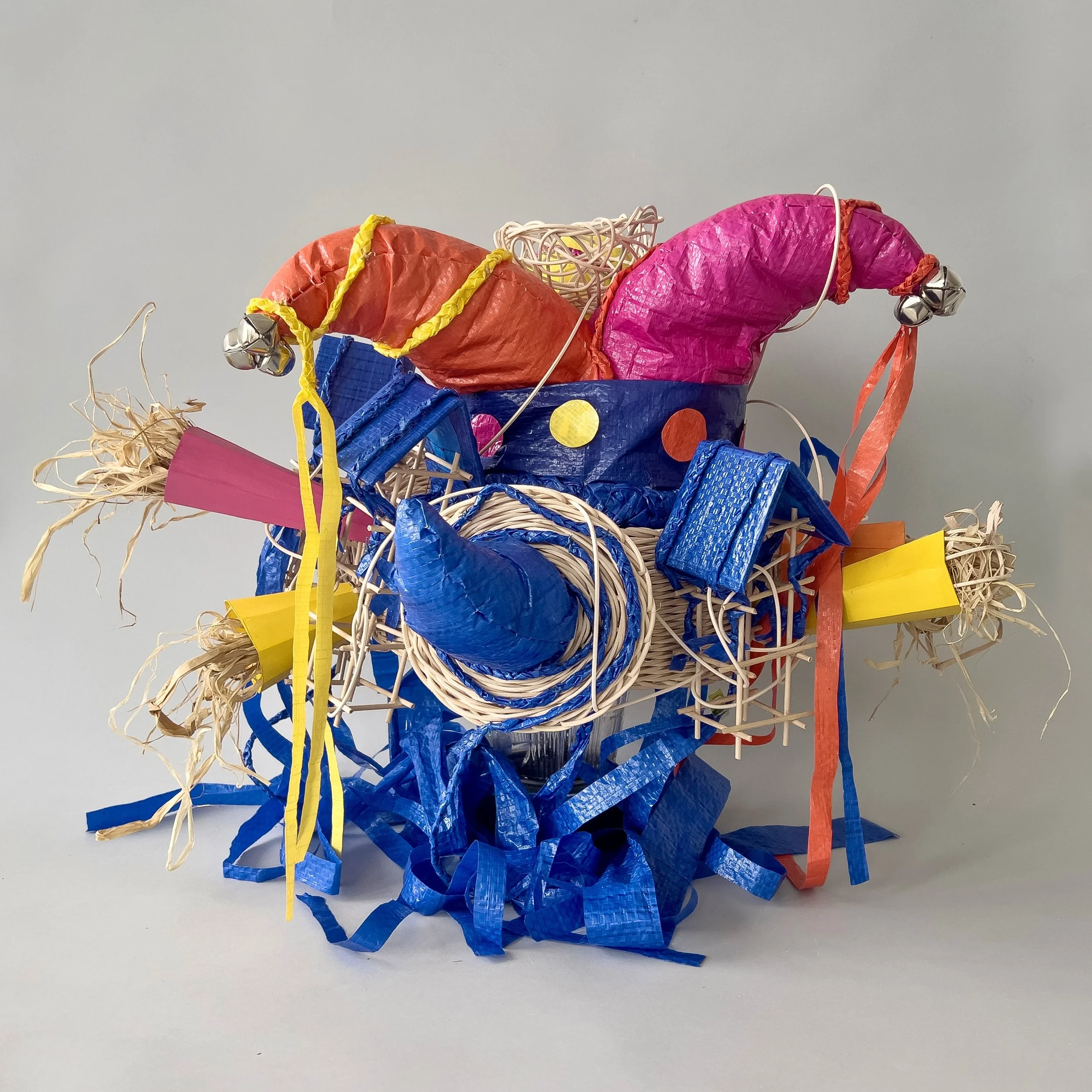 Her Lover / 2026 / Plastic, reed / 16"x18"x15"/ Wearable hat made up of silenced tornado sirens, jester hat and houses for trumpet performer in "Love Letters". This head piece is worn by the performer who represents the weather station NOAA Station 8
