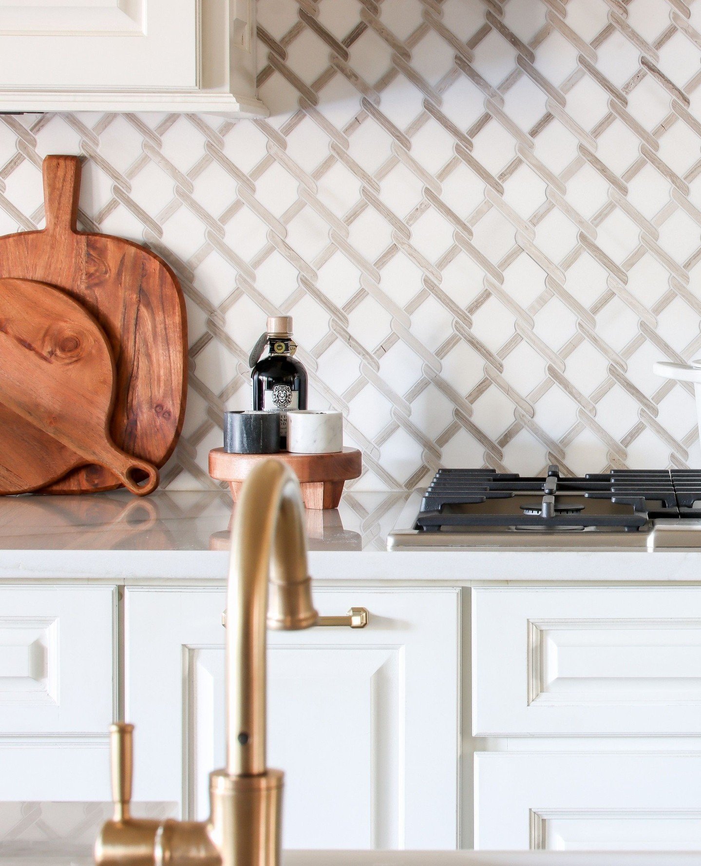 Elevate your kitchen's style with a tile design that makes a statement. The unique pattern and soft hues of these tiles provide a backdrop of sophistication, seamlessly blending with the lustrous gold hardware for a look that&rsquo;s both chic and ti