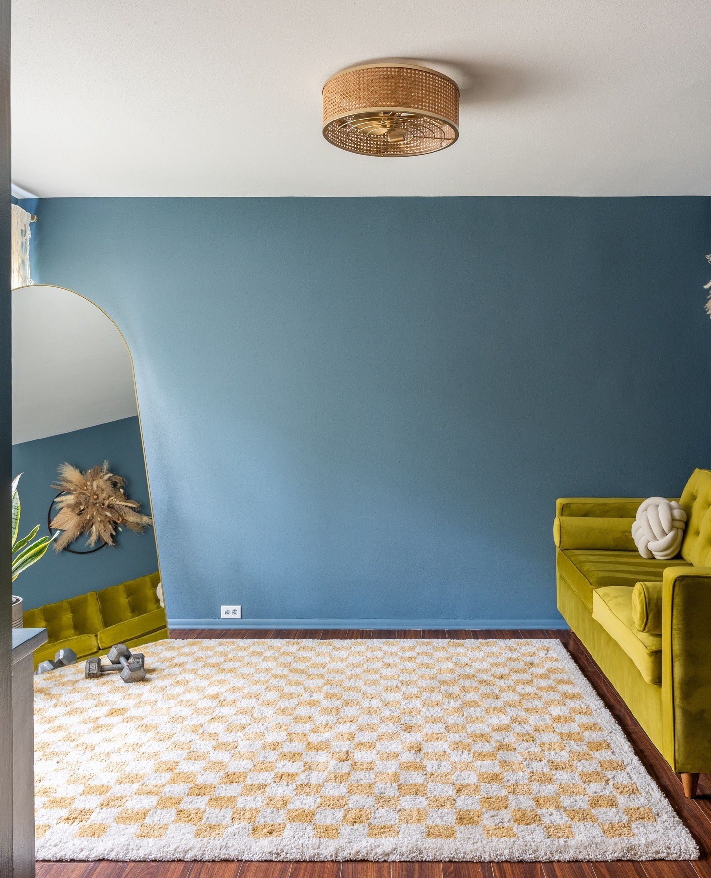 Who says dark colors make a room feel small? This space proves just the opposite. The deep teal walls add a vibrant backdrop that brings energy and personality without compromising the room's openness. Paired with rich flooring and natural textures l