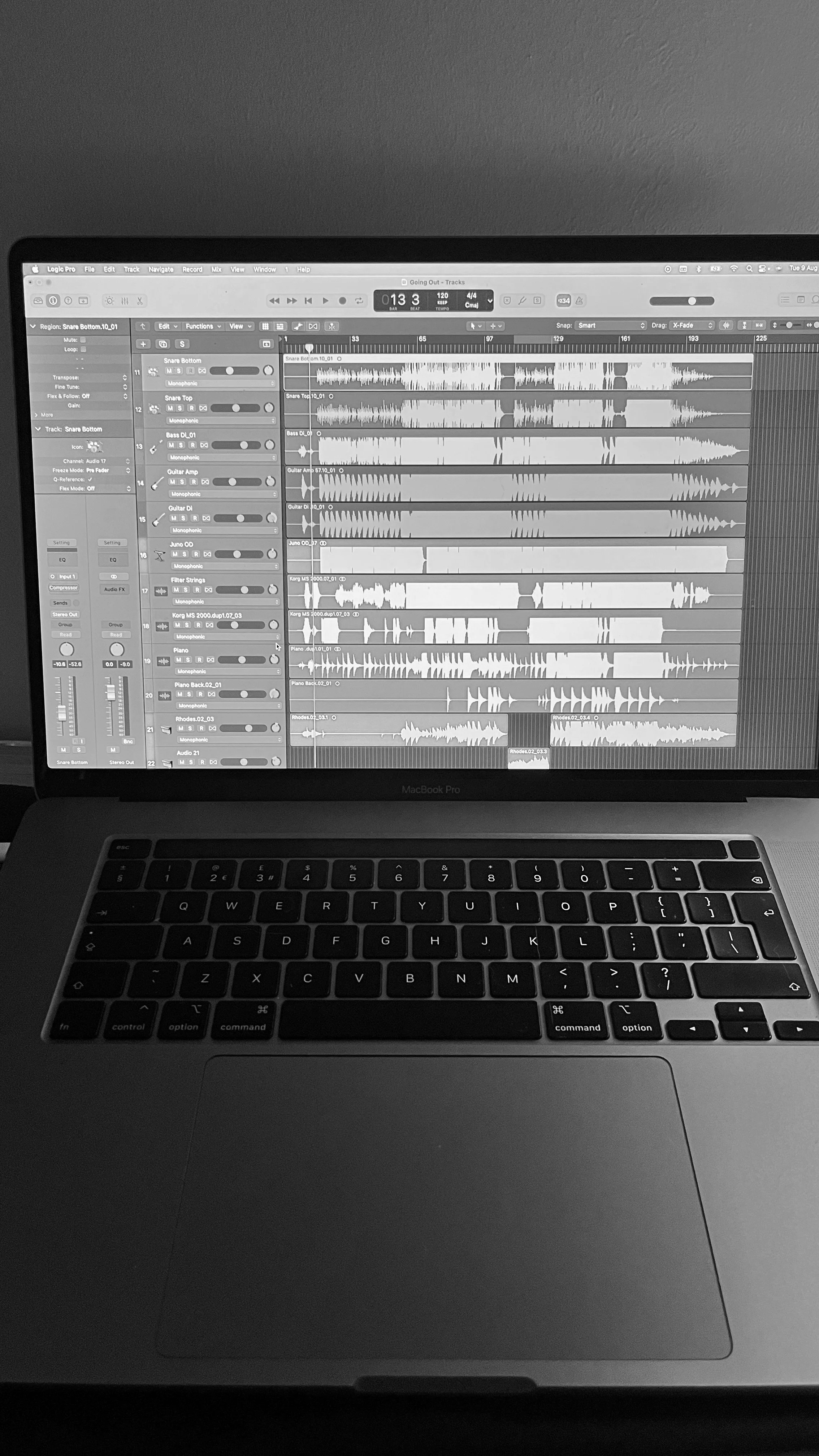 A MacBook Pro displaying digital audio workstation software with multiple tracks of audio waveforms and controls.