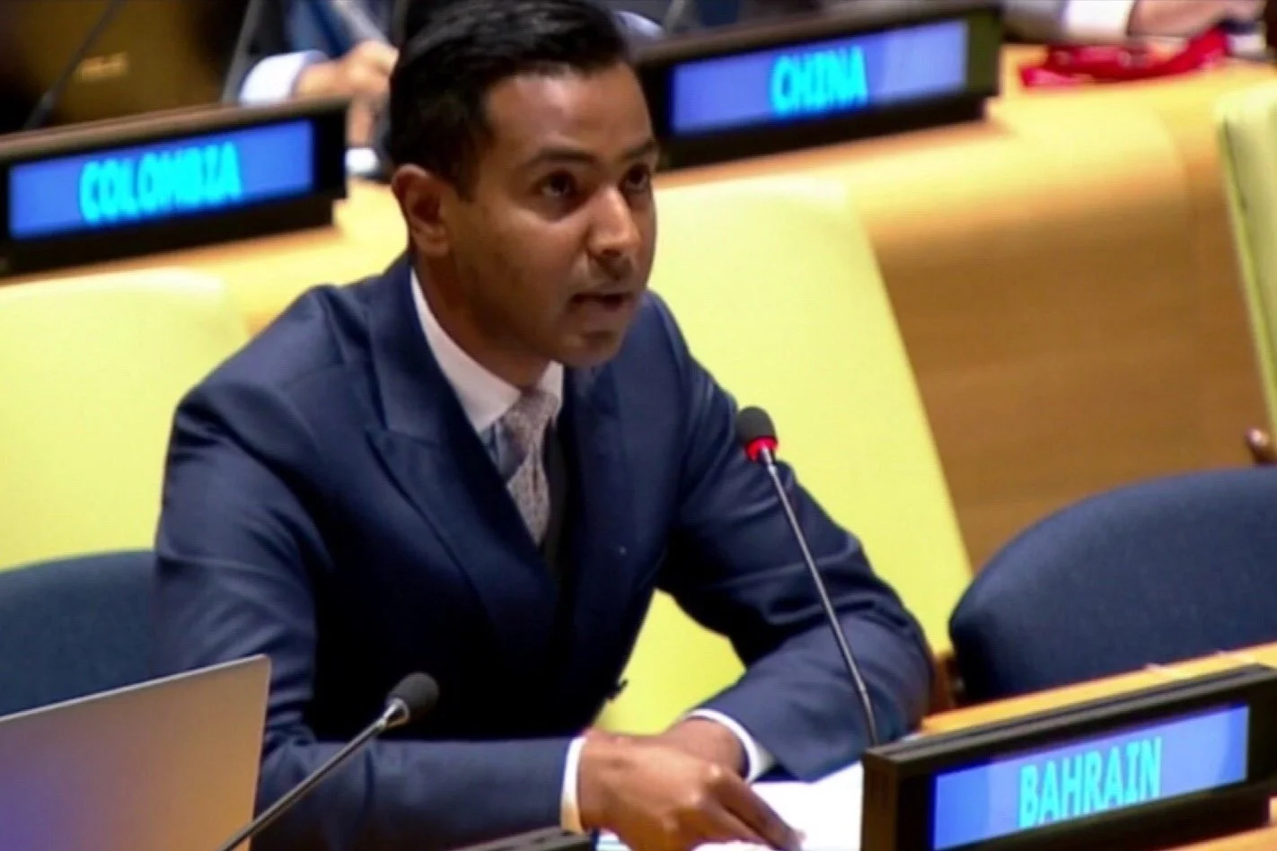 A man in a dark suit speaking into a microphone at a United Nations meeting. The nameplate in front of him reads 'Bahrain'. In the background, there is a sign that reads 'Colombia'.