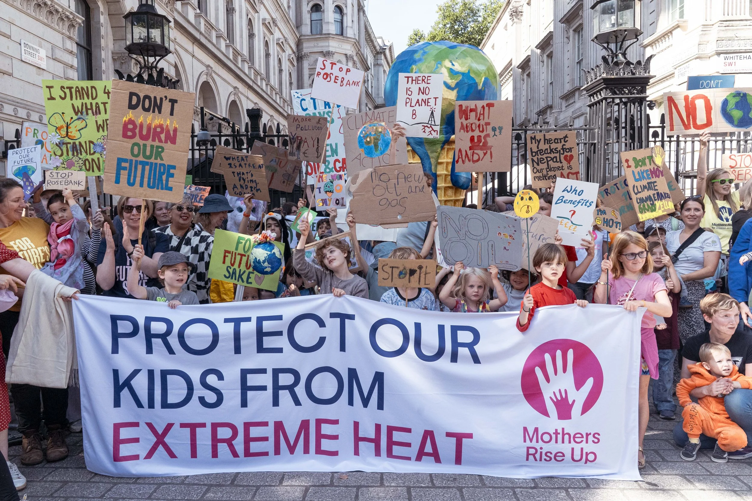 September 2026: MRU, our giant melting planet ice-cream and over 150 mothers, grandmothers, caregivers and children meet outside the gates to 10 Downing Street to urge Andy Burnham to take decisive action to stop new oil and gas, invest in clean home