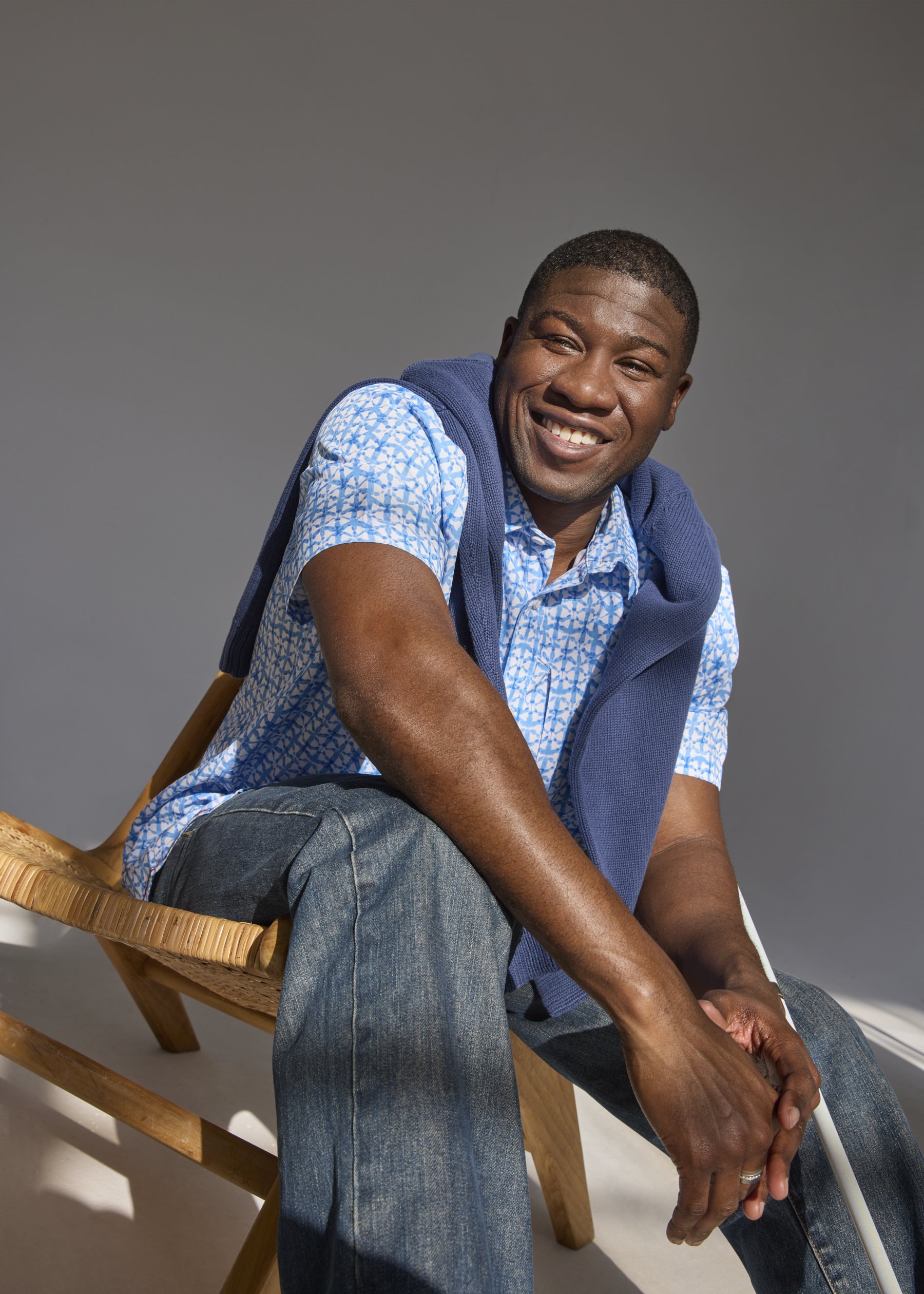 Ben_083_Sitting_on_chair_in_sunshine_laughing_looking_at_camera_with_sweater_over_shoulders.jpg